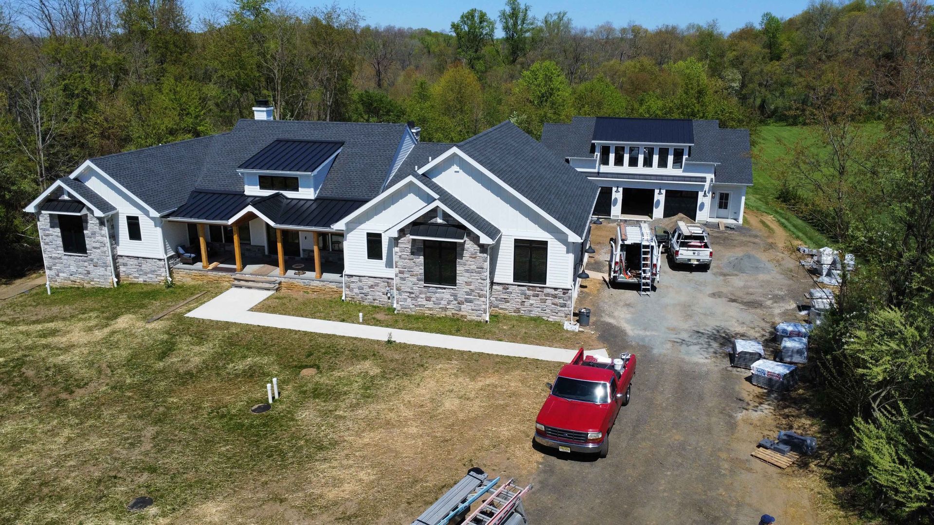 An aerial view of a large house under construction with a red truck parked in front of it.