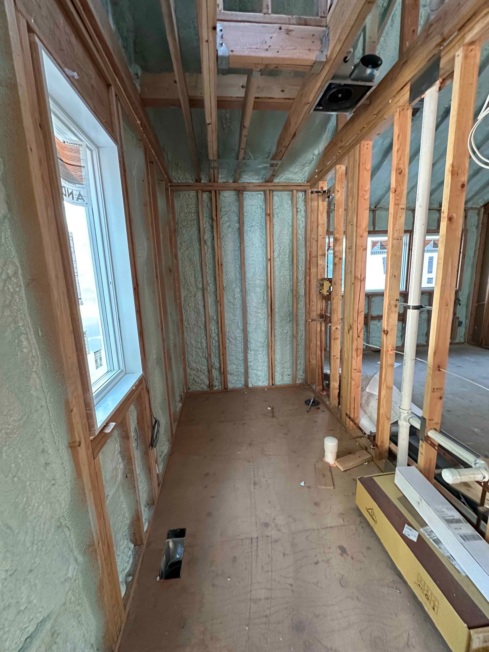 A room with a lot of wooden beams and foam insulation on the walls.