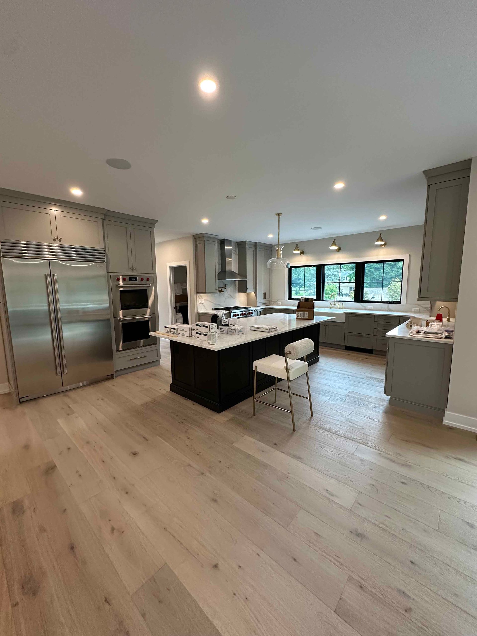 A kitchen with stainless steel appliances , hardwood floors , and a large island.
