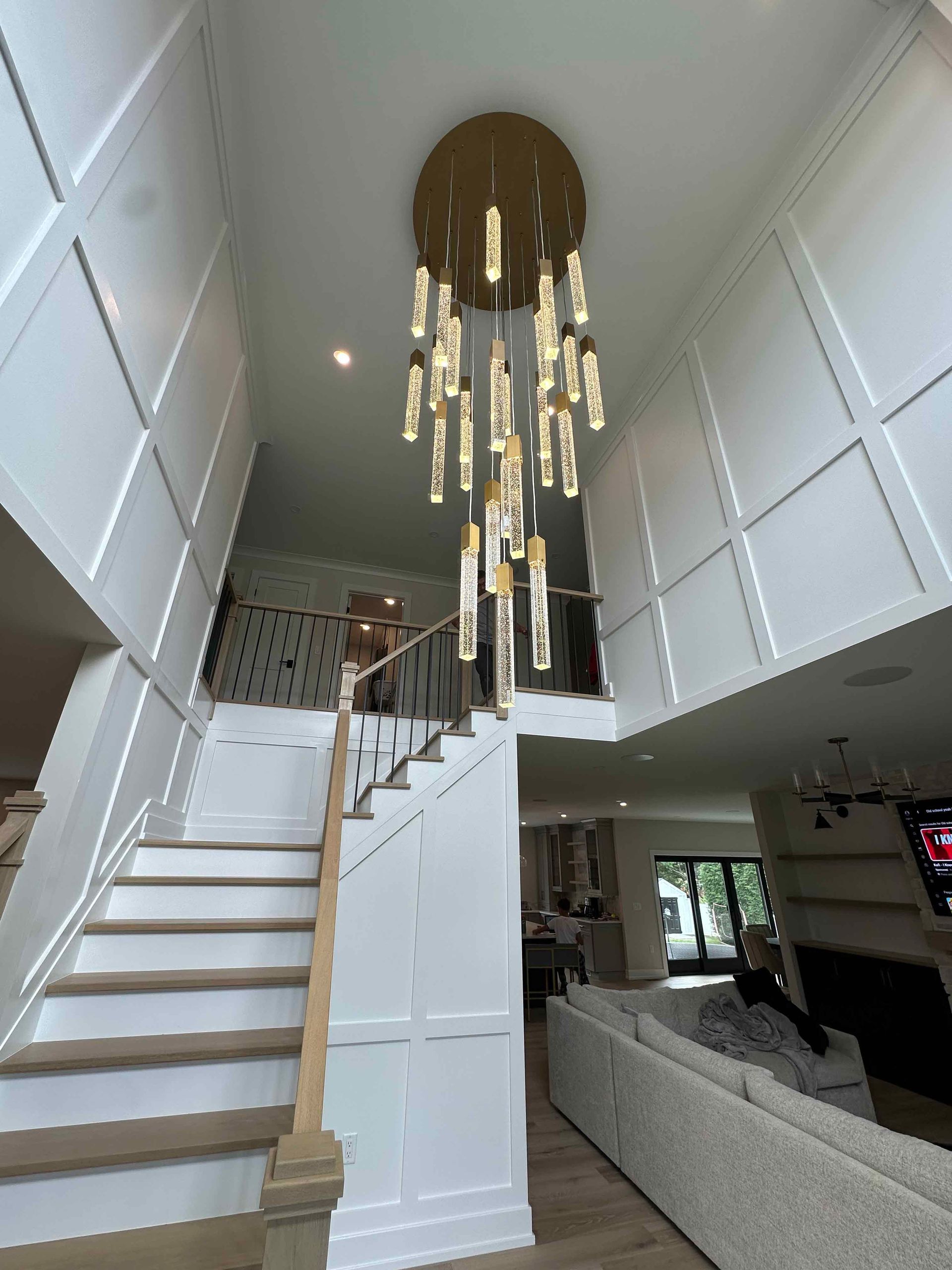 A living room with stairs and a chandelier hanging from the ceiling.