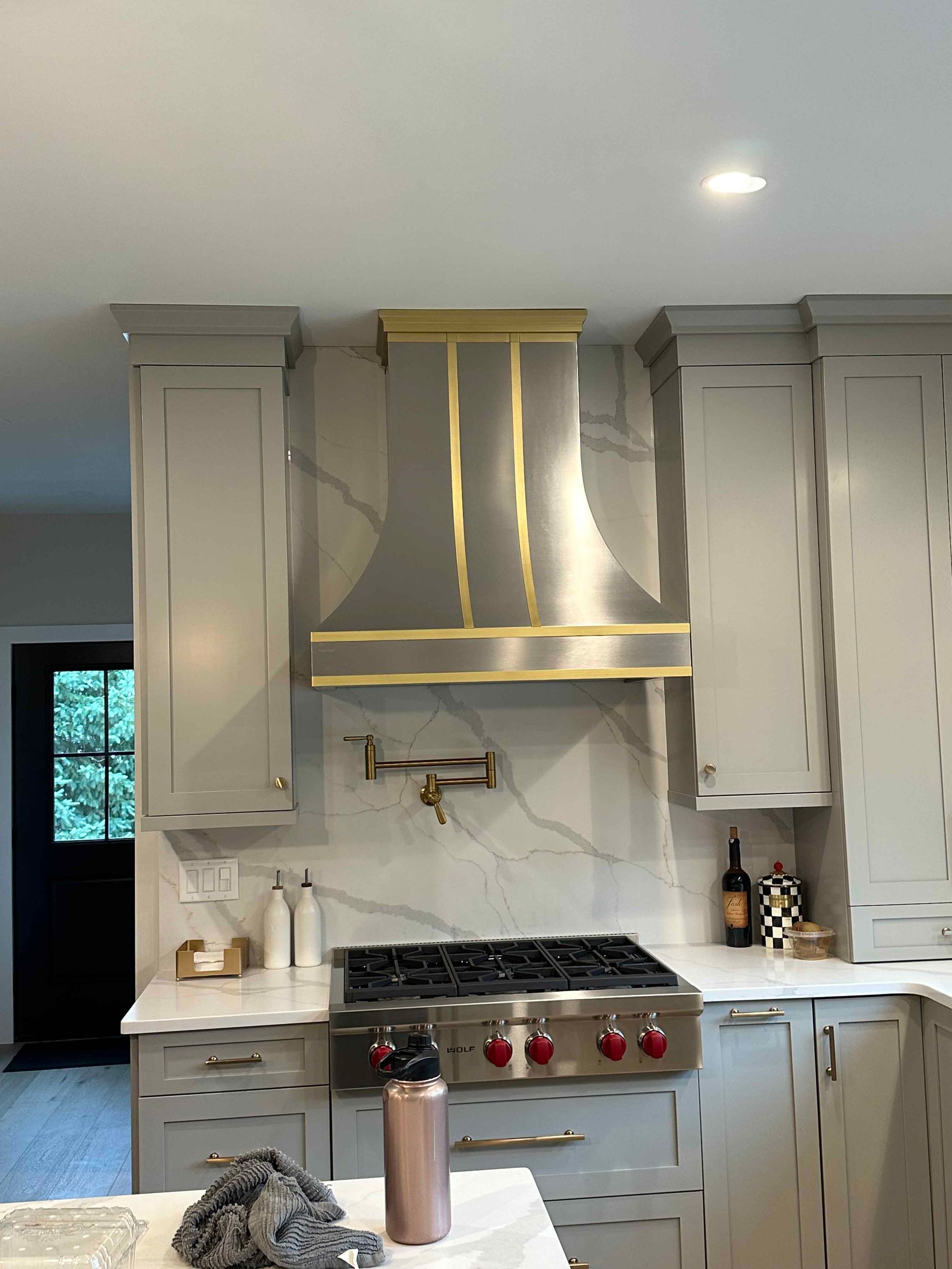 A kitchen with a stove and a hood above it.