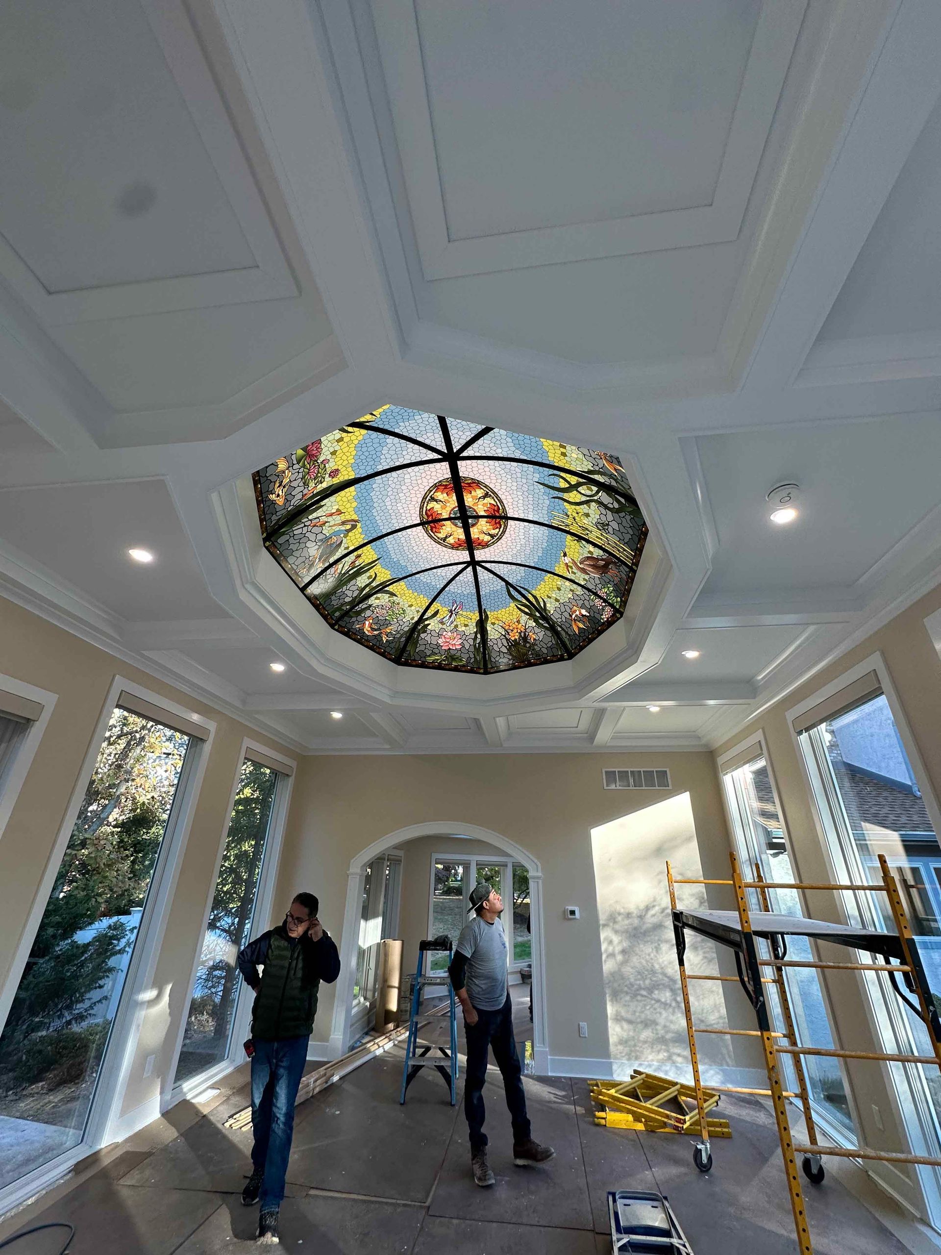 A man is standing in a room with a stained glass dome on the ceiling.