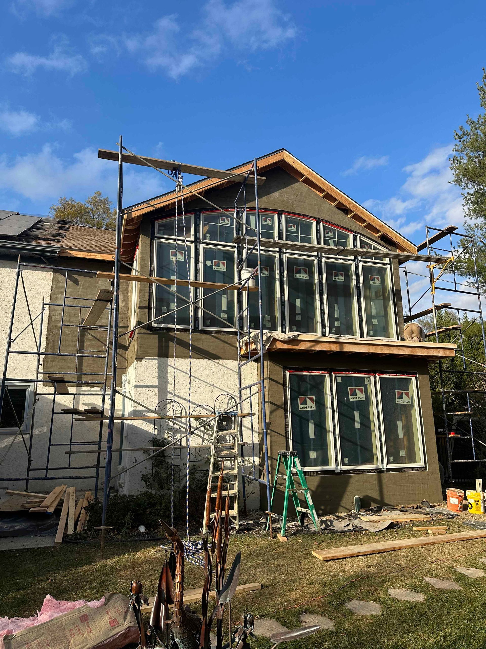 A house is being remodeled with scaffolding and a lot of windows.