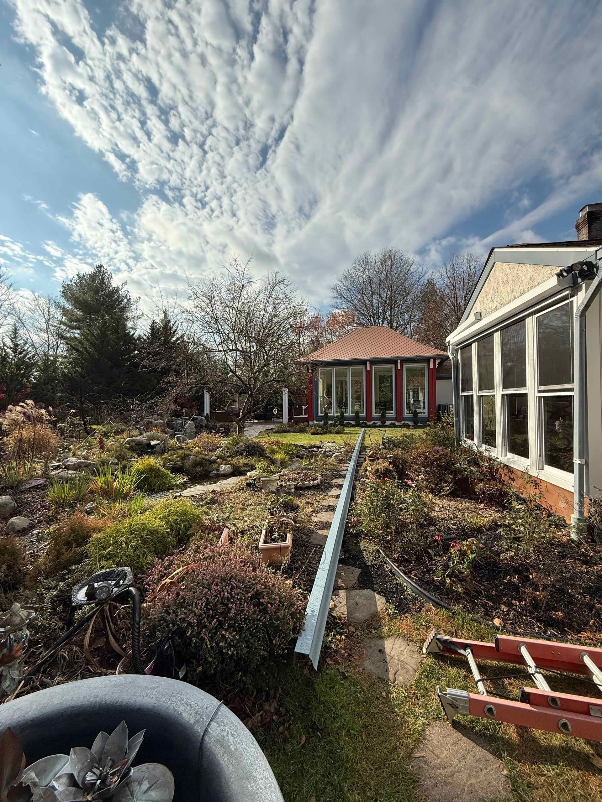A garden with a house in the background and a ladder in the foreground.