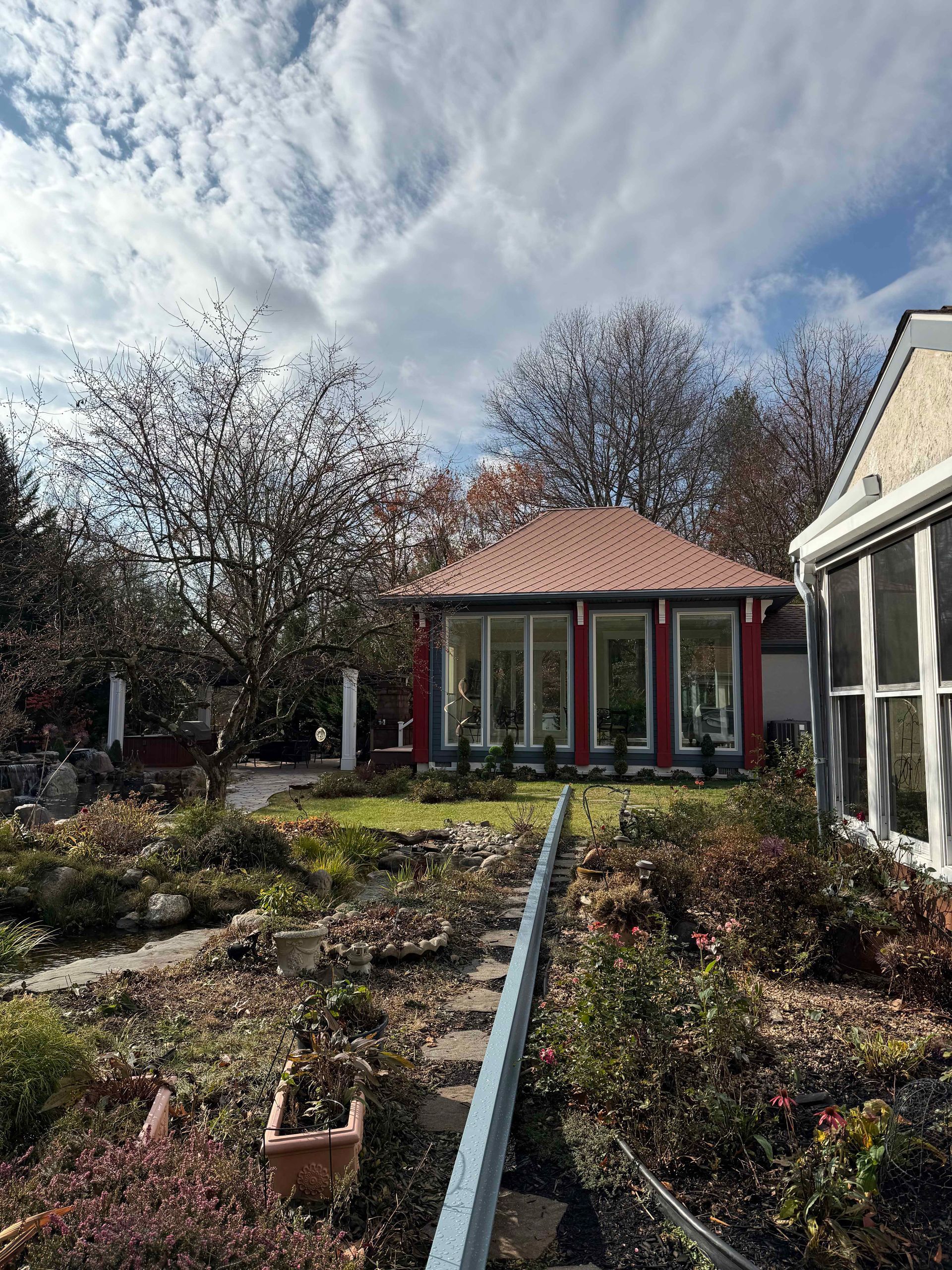 A small house with a red roof is surrounded by trees and bushes.