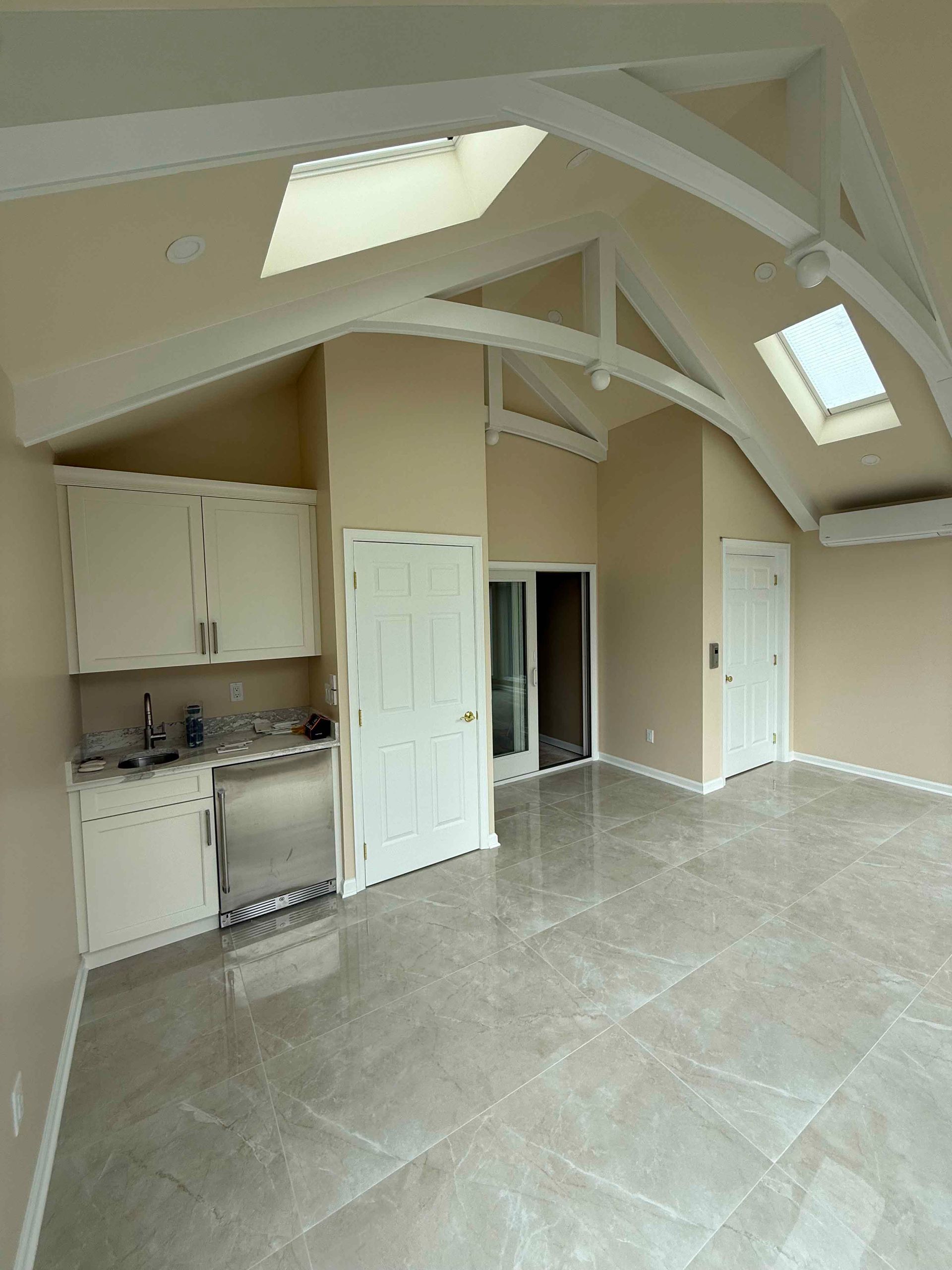 A large empty room with a vaulted ceiling and a skylight.