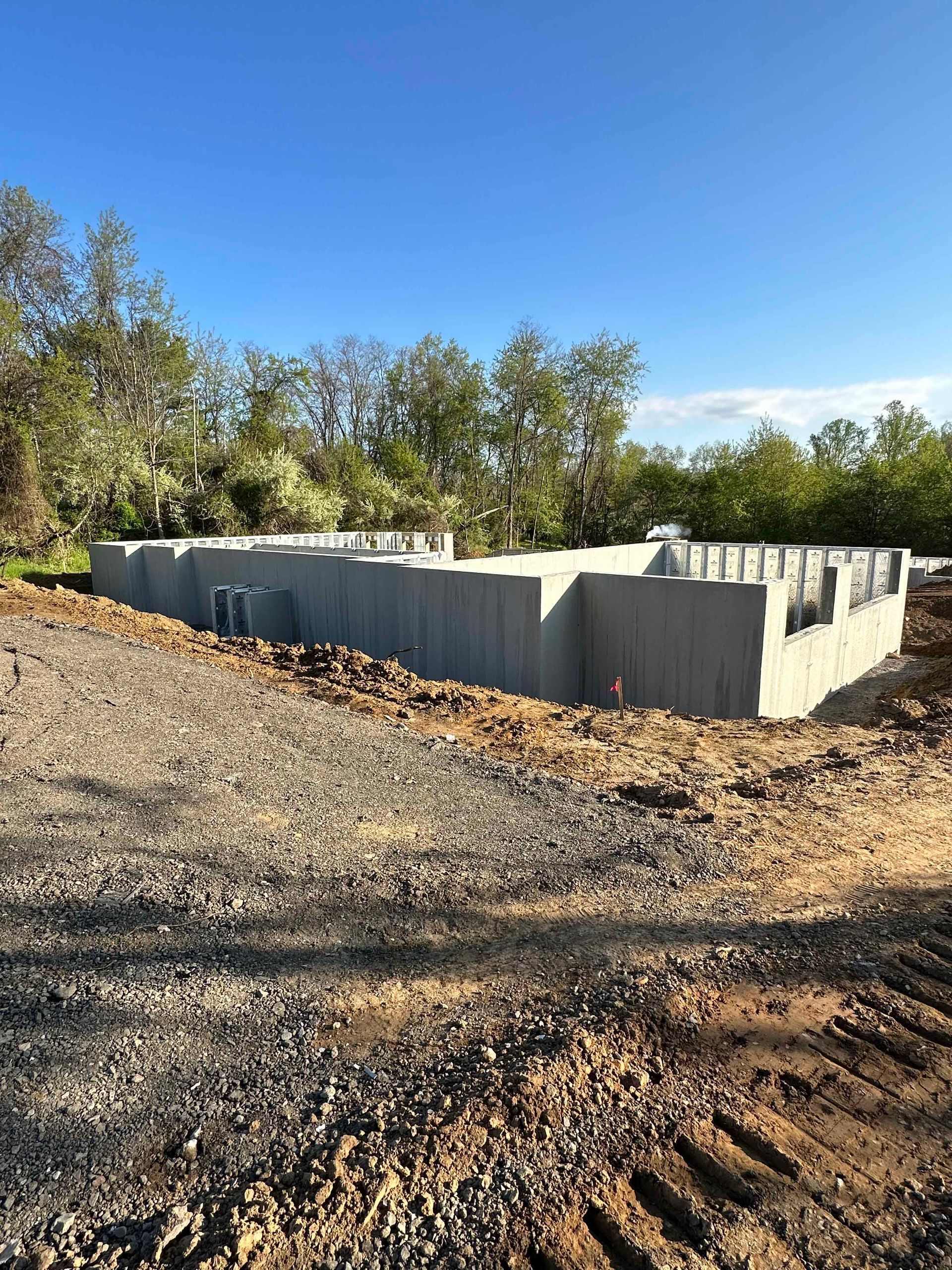 A concrete foundation is being built in the middle of a dirt field.