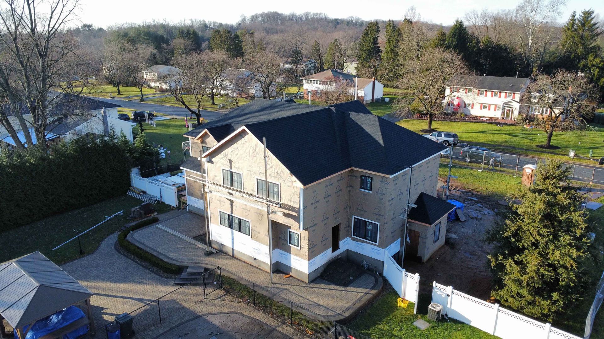 An aerial view of a house with a black roof in a residential area.
