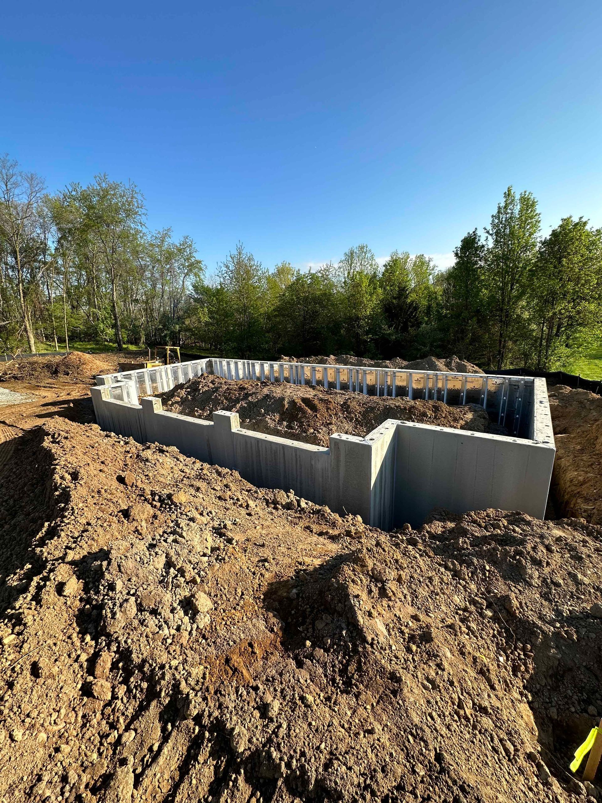 A concrete foundation is being built in a dirt field.