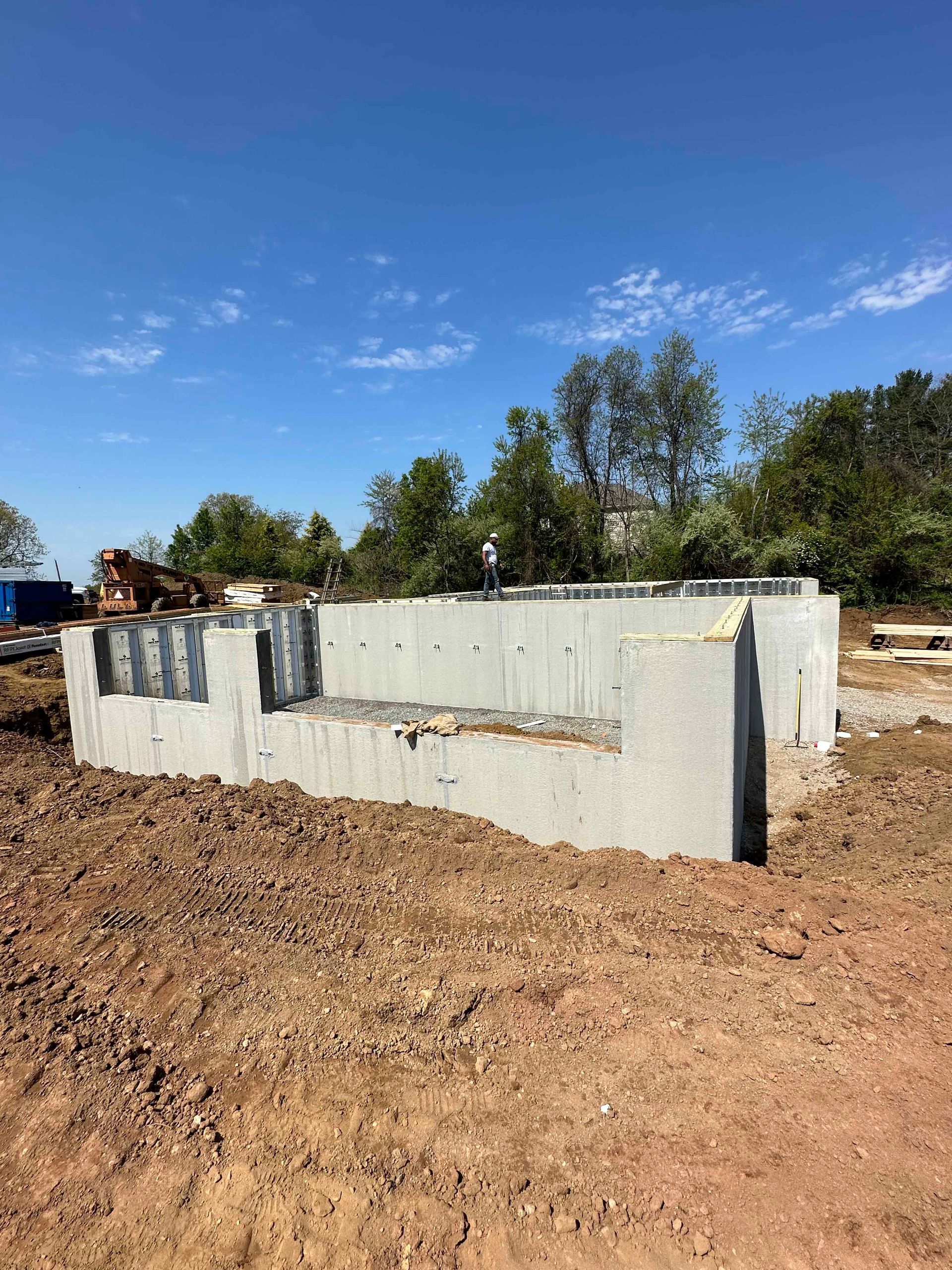 A large concrete wall is sitting in the middle of a dirt field.