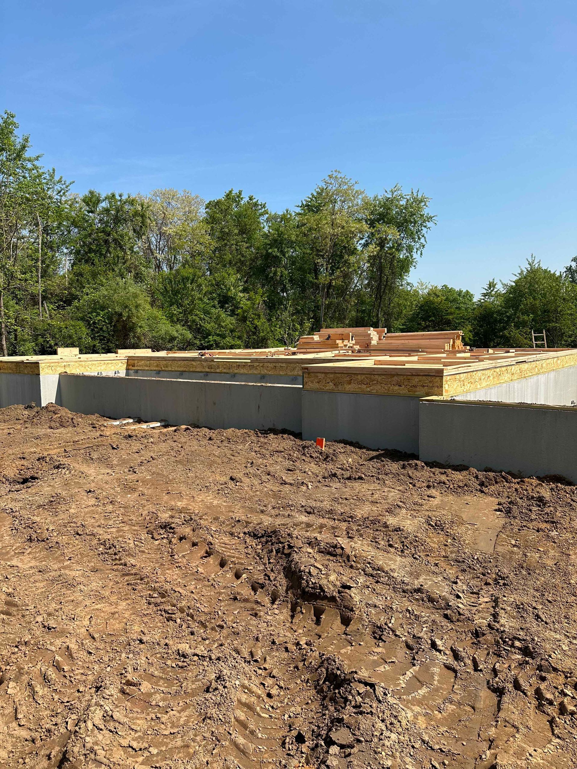 A construction site with a lot of dirt and trees in the background.