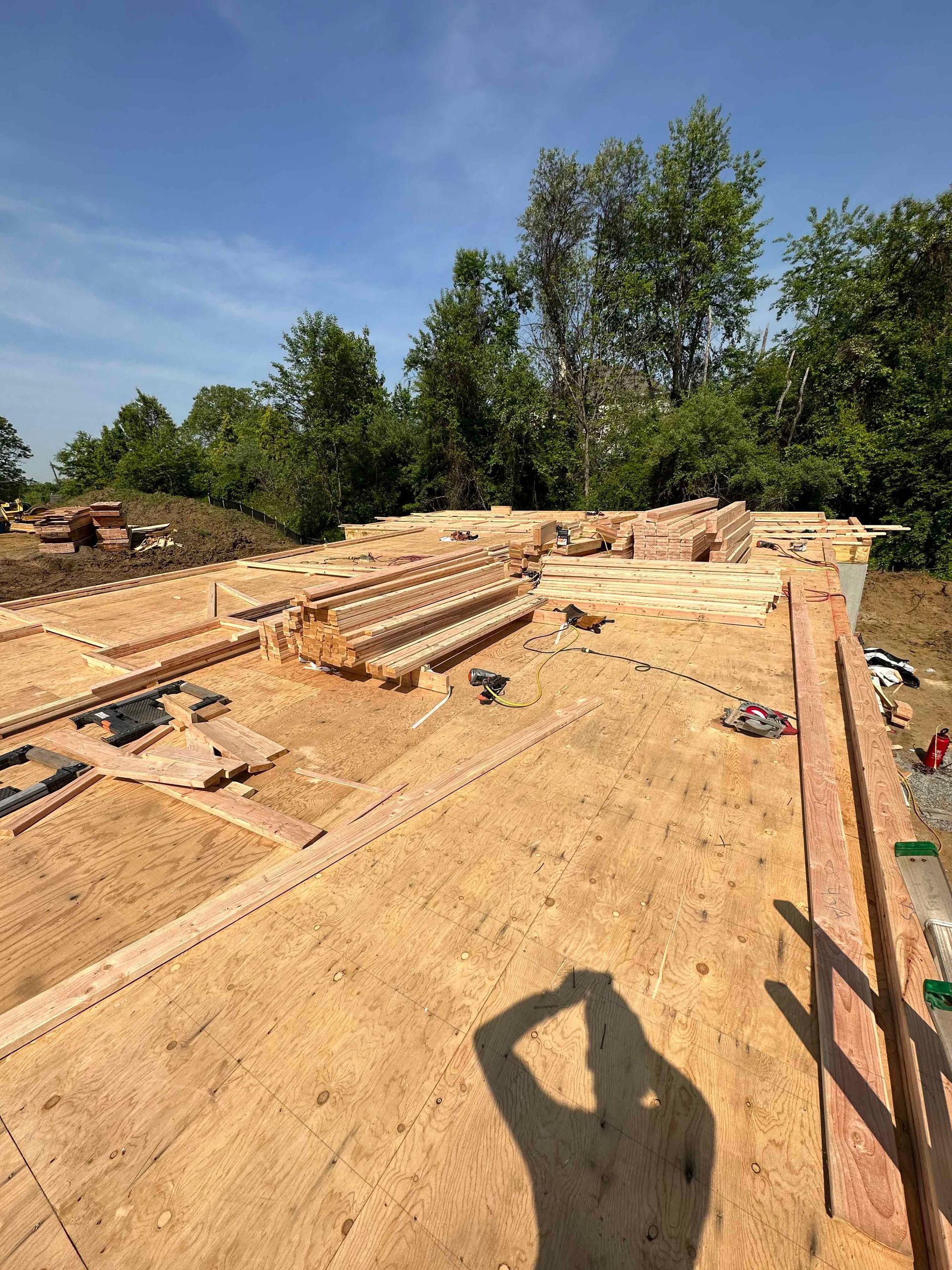 A person is standing on top of a wooden roof under construction.