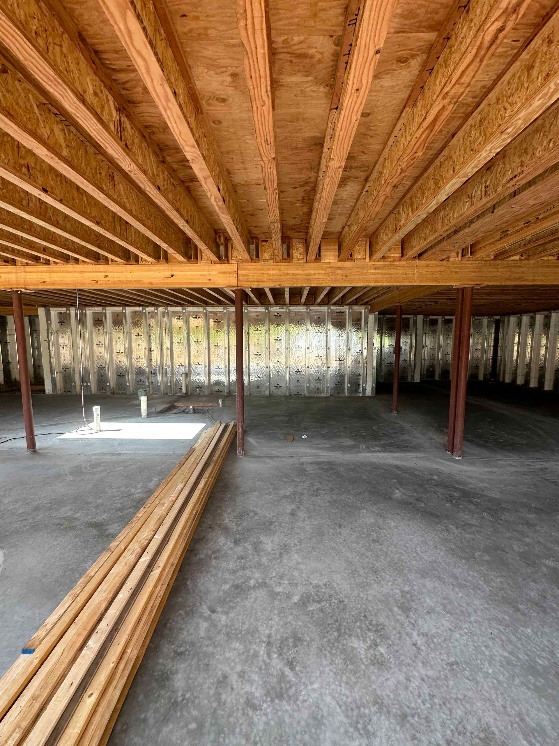 A large empty room with wooden beams and a concrete floor.