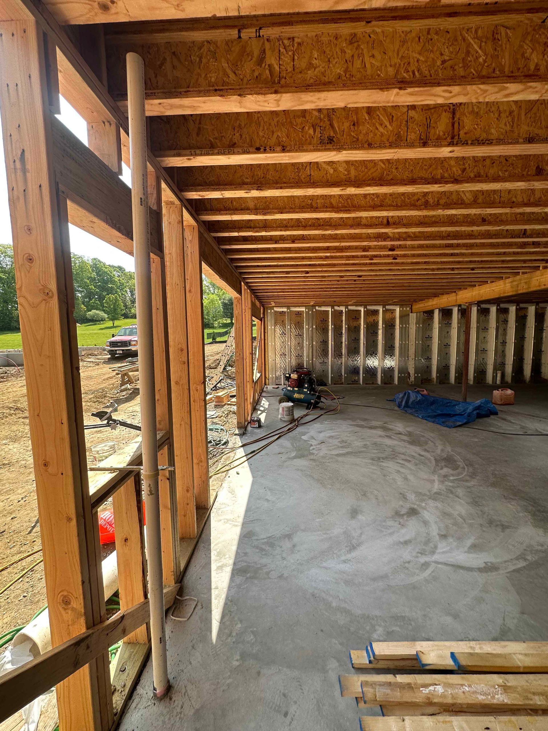 A building under construction with wooden beams and a concrete floor.