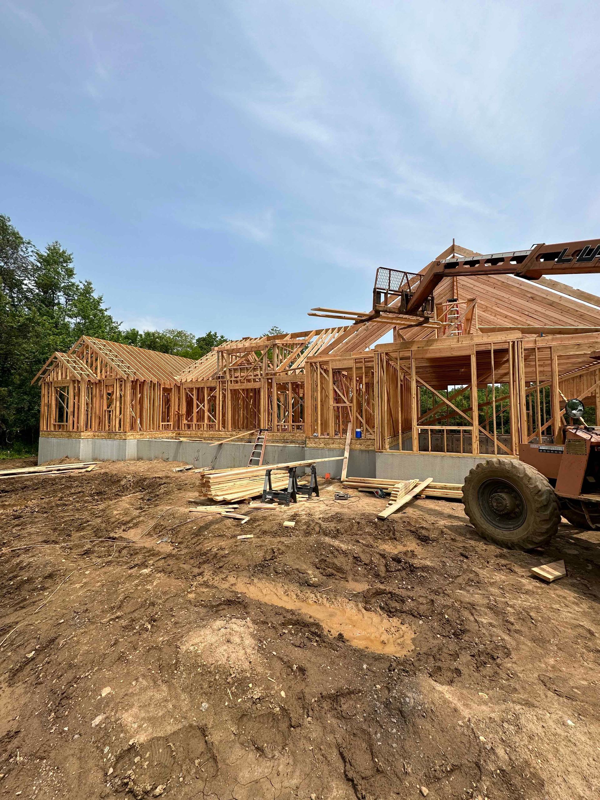 A large house is being built in the middle of a dirt field.