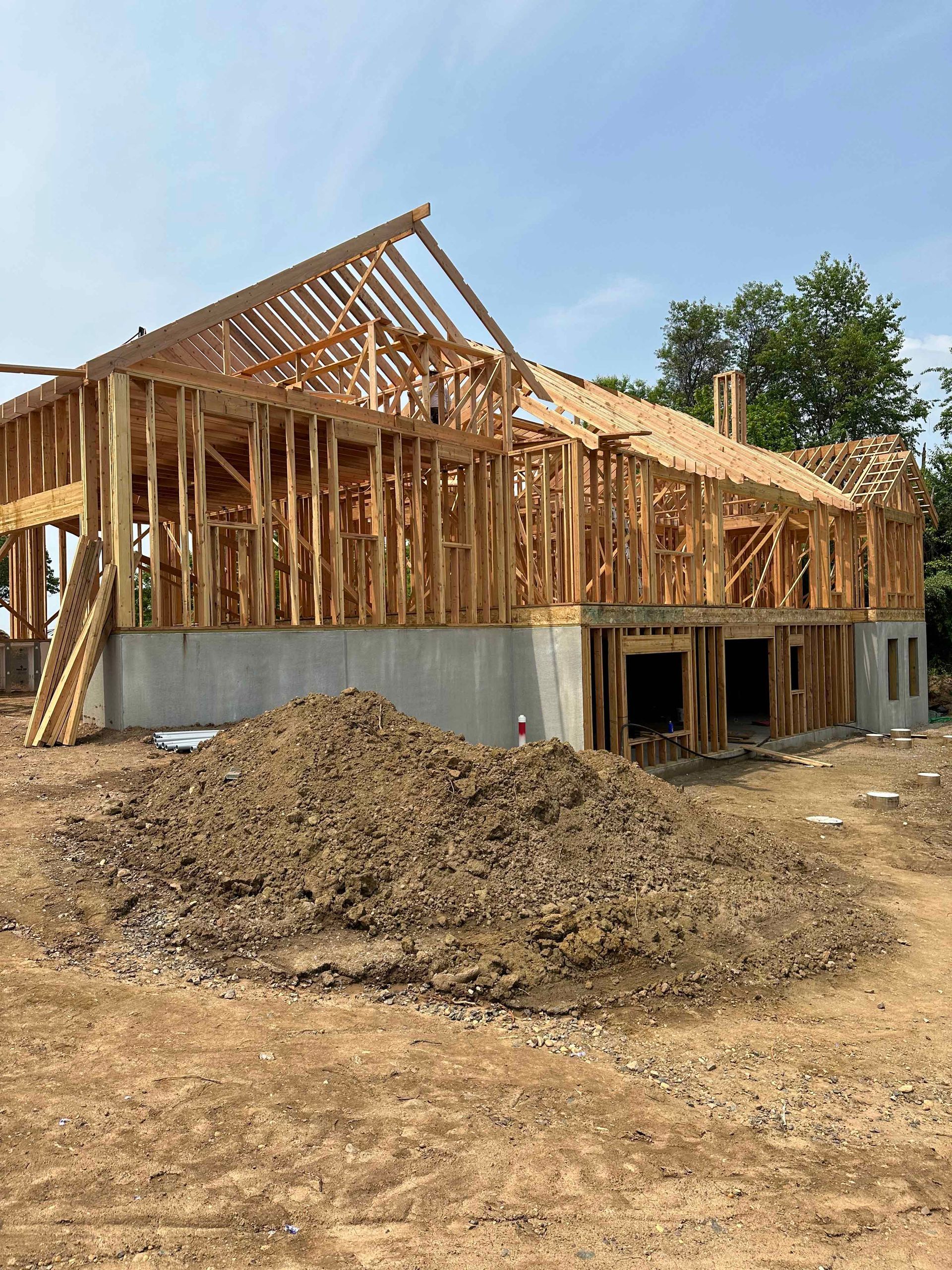 A large wooden house is being built in a dirt field.
