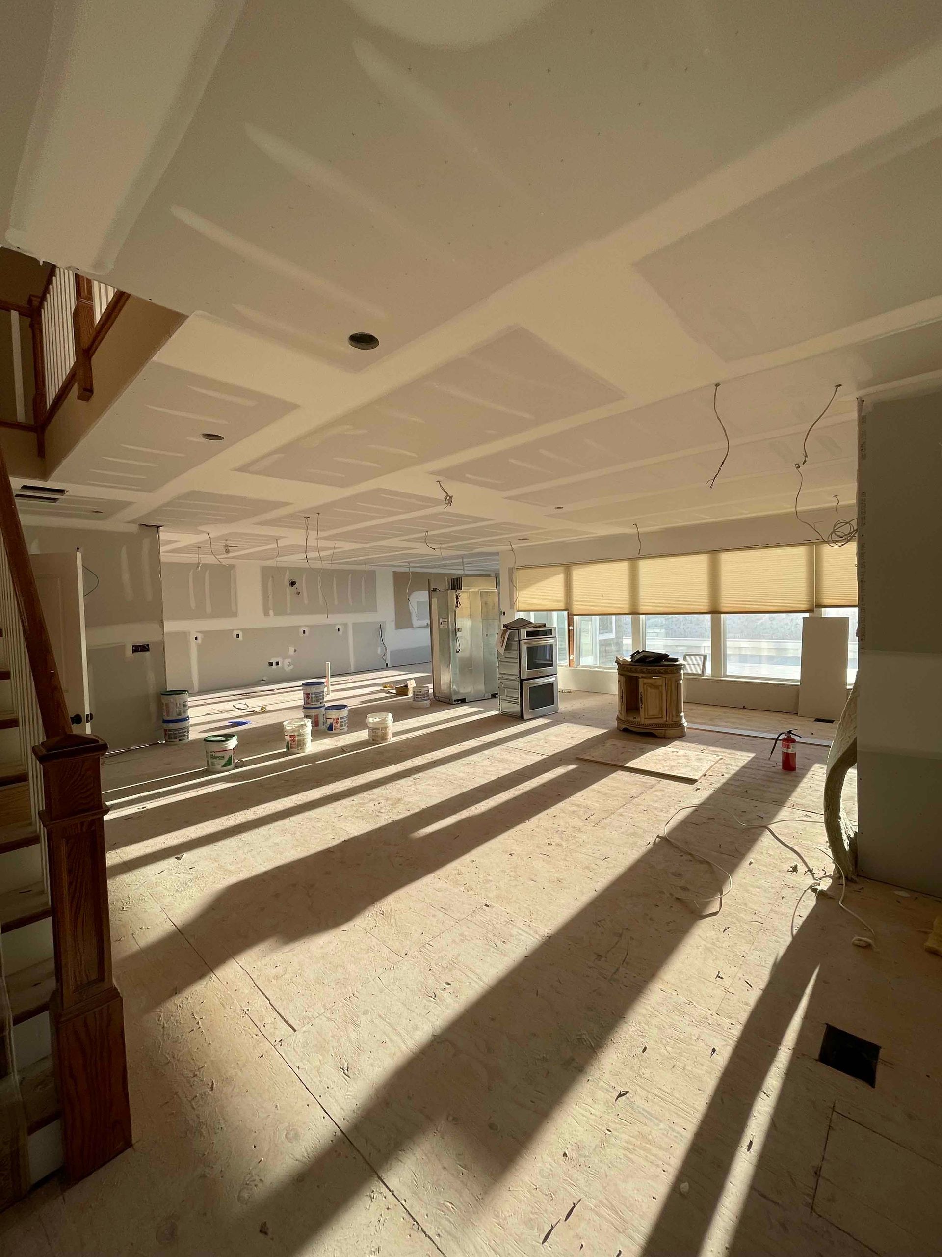 A large room with a staircase and a lot of windows under construction.