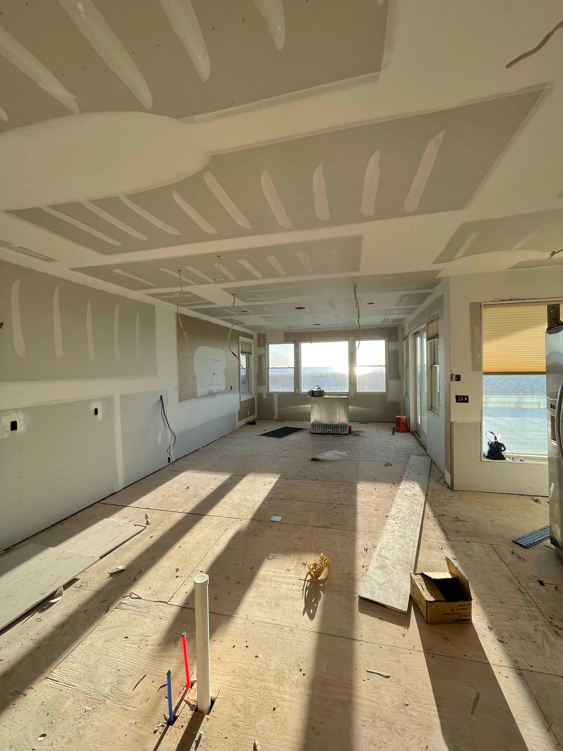 A large room that is being remodeled with a lot of windows