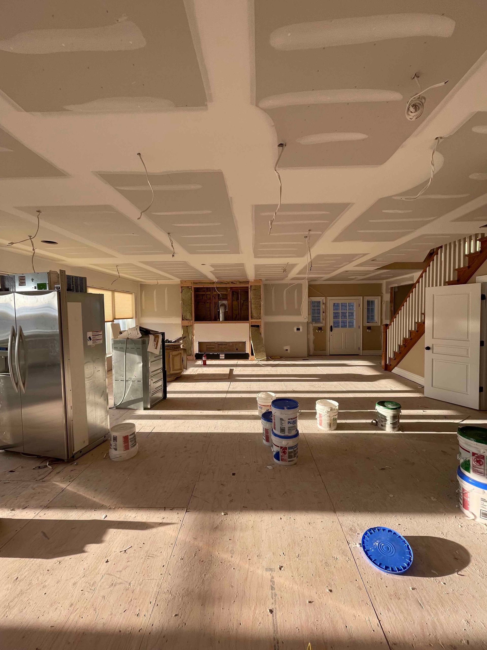 A large room with a lot of buckets of paint on the floor.