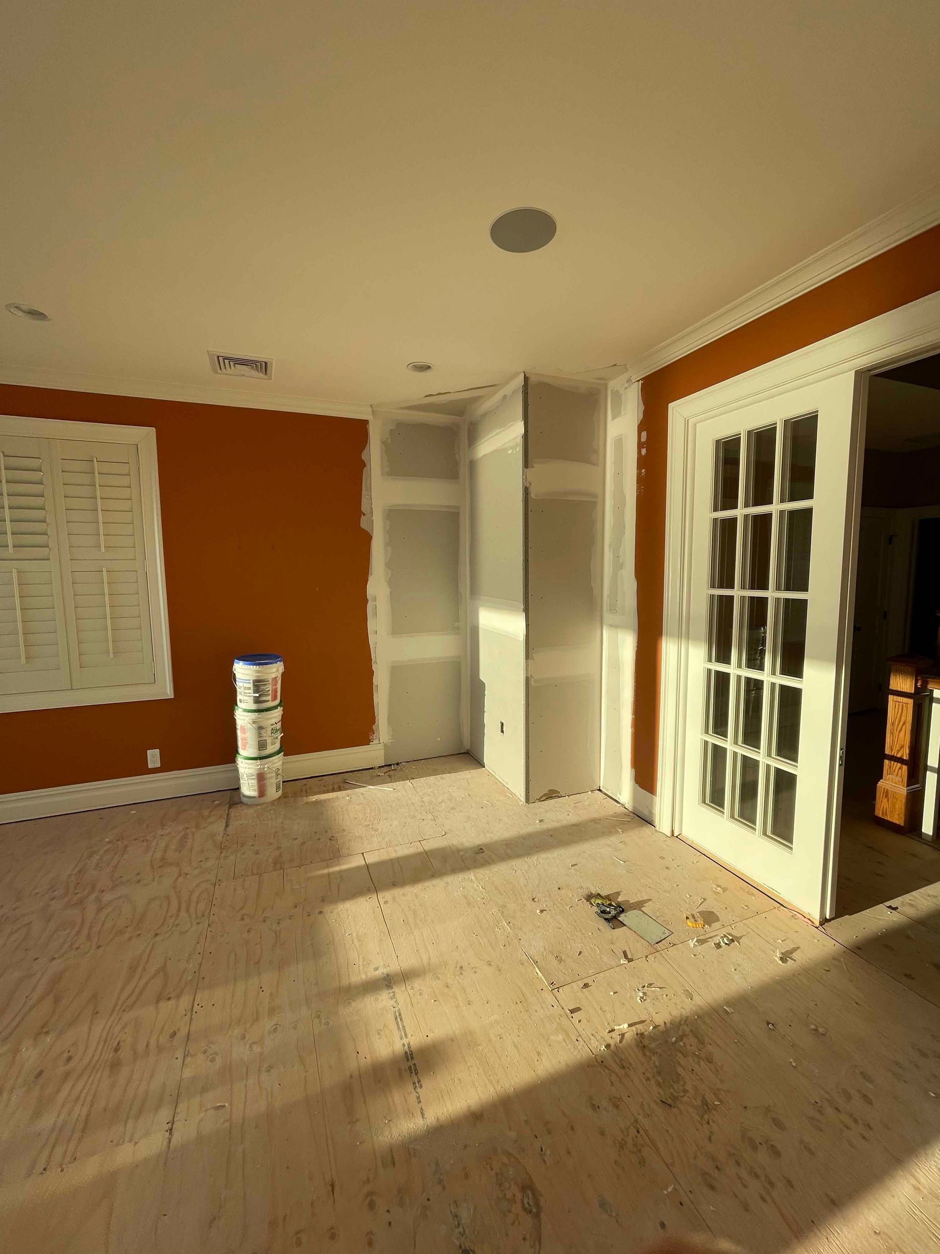 An empty room with a few buckets of paint on the floor