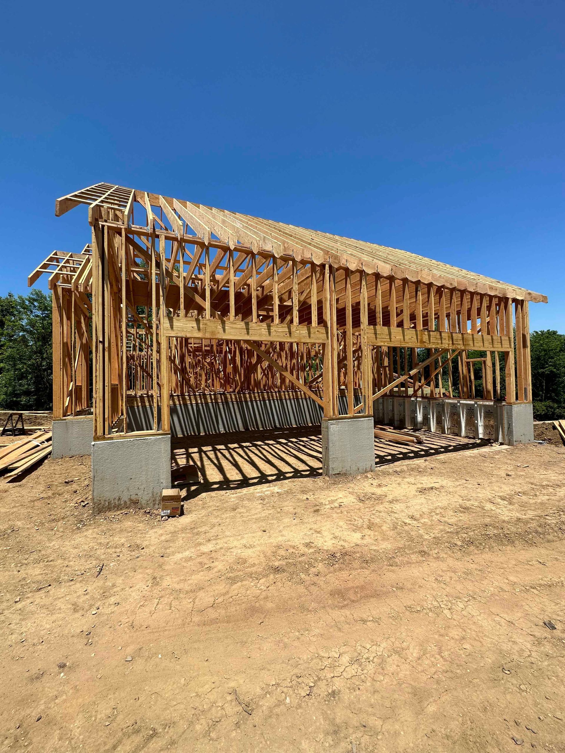 A large wooden structure is being built in a dirt field.