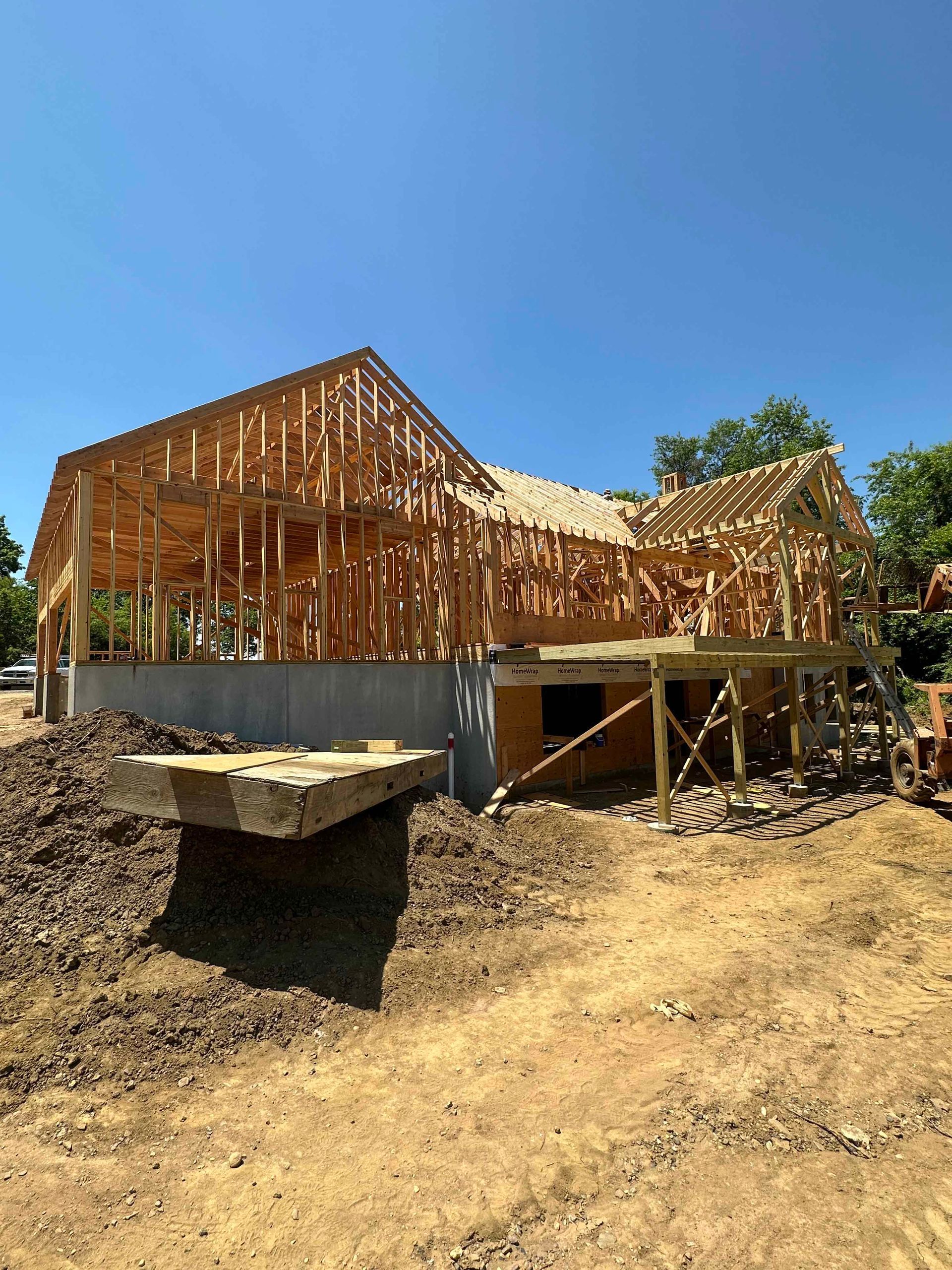 A large wooden house is being built in a dirt field.