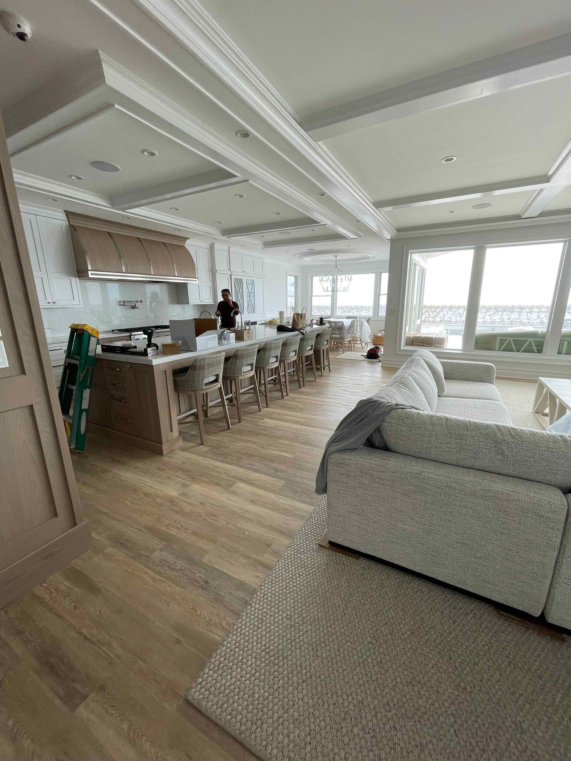 A living room filled with furniture and a kitchen with a view of the ocean.