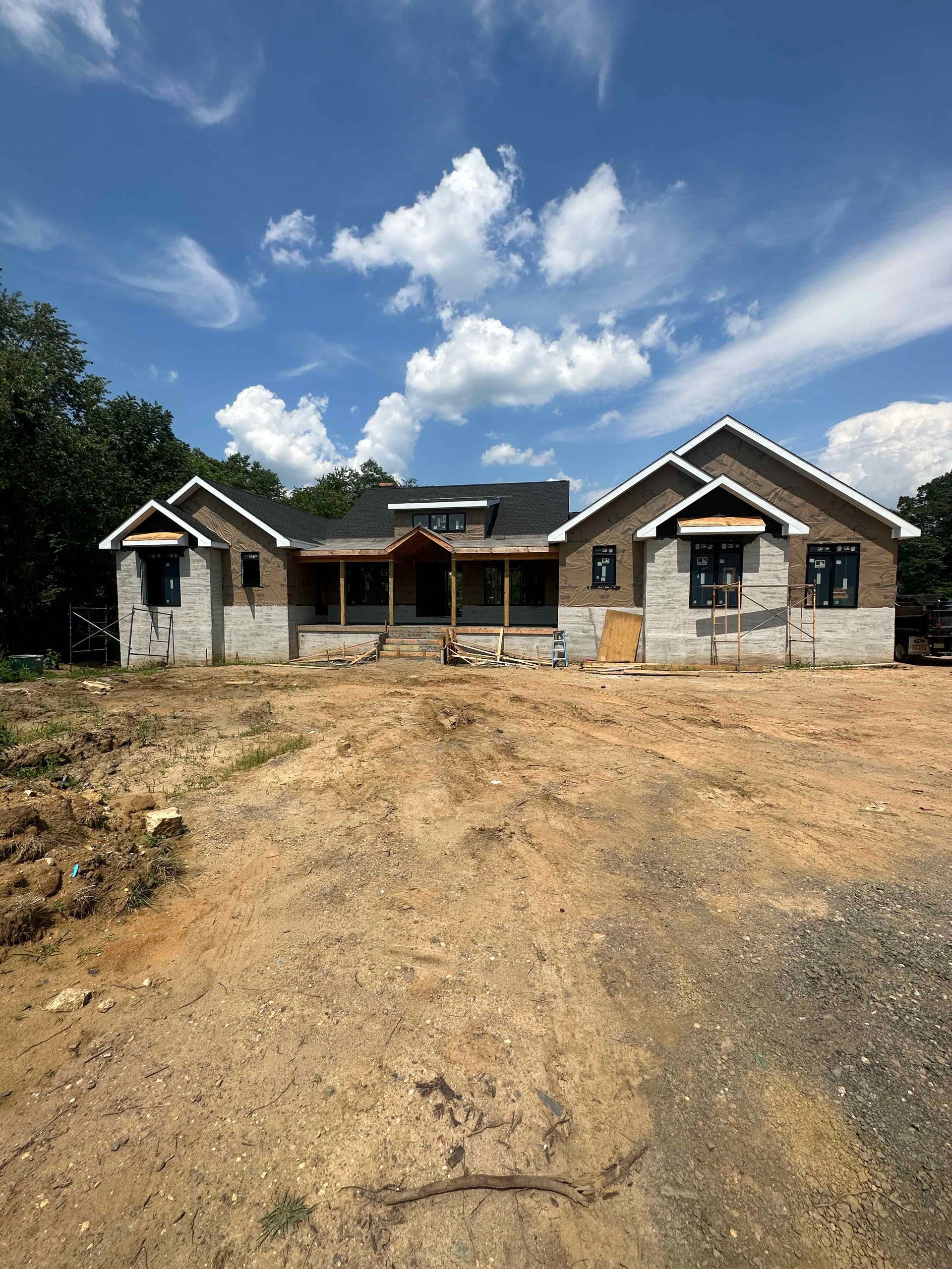 A large house is being built in the middle of a dirt field.