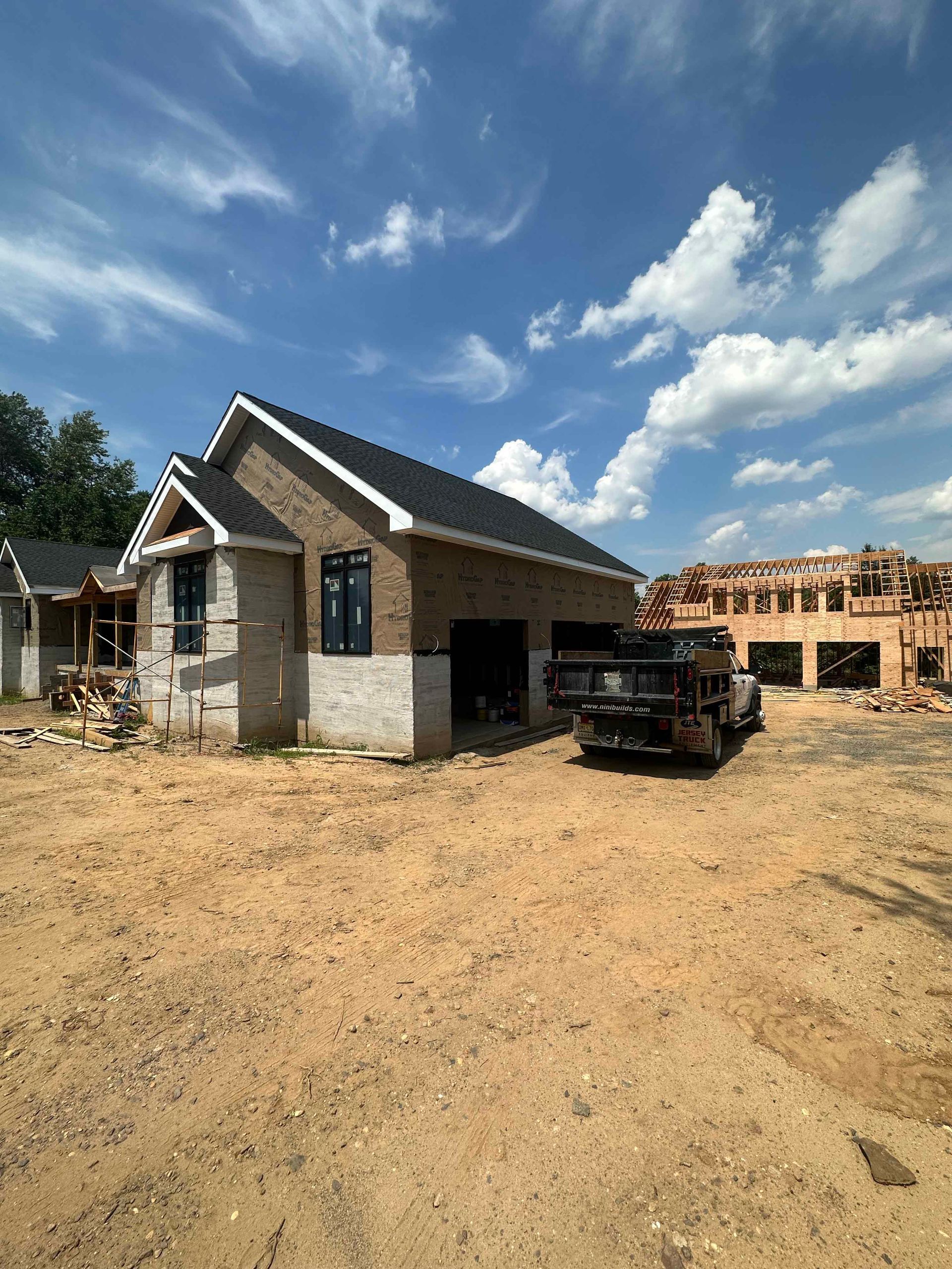A truck is parked in front of a house under construction.