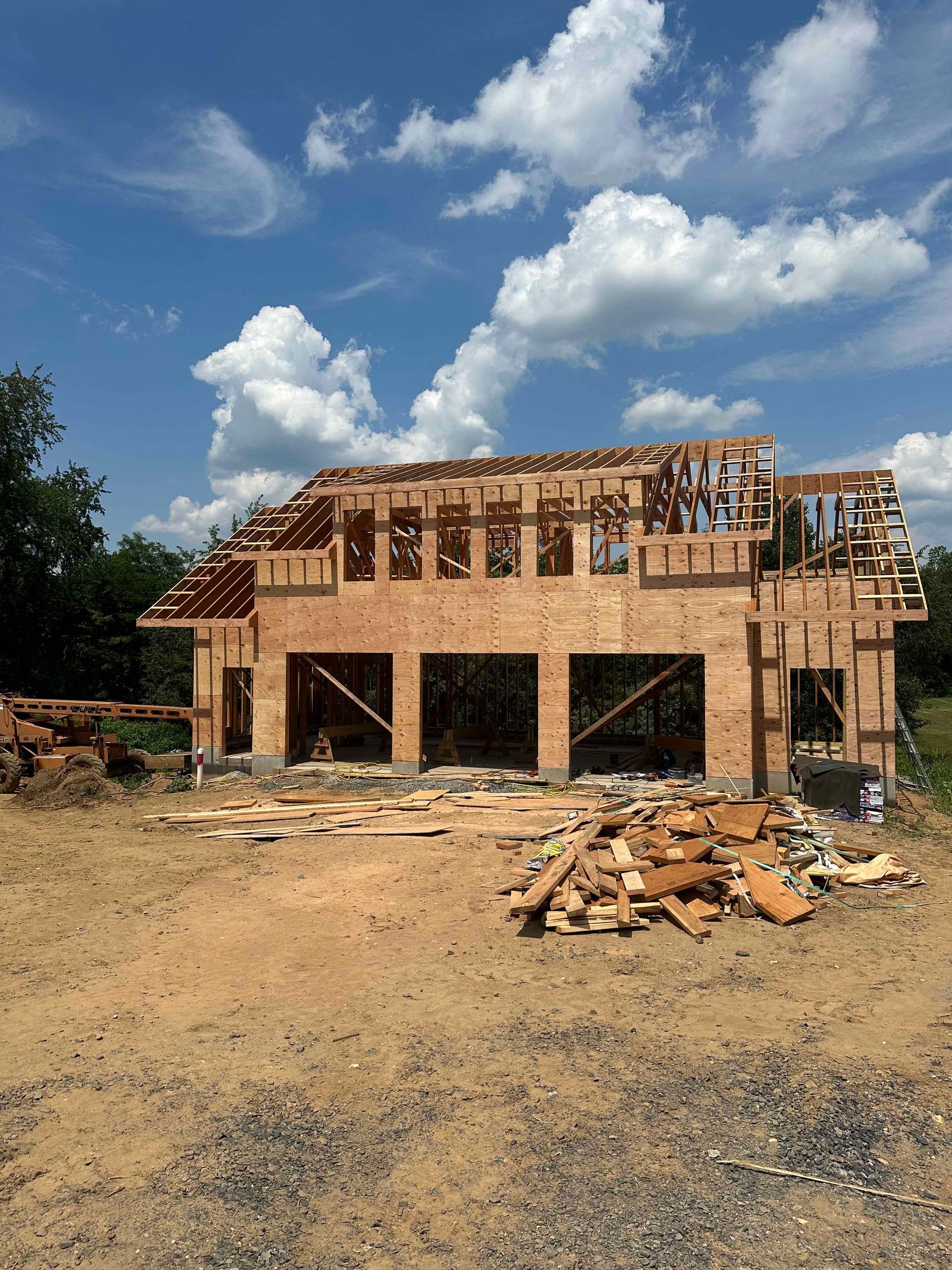 A large wooden house is being built in a dirt field.