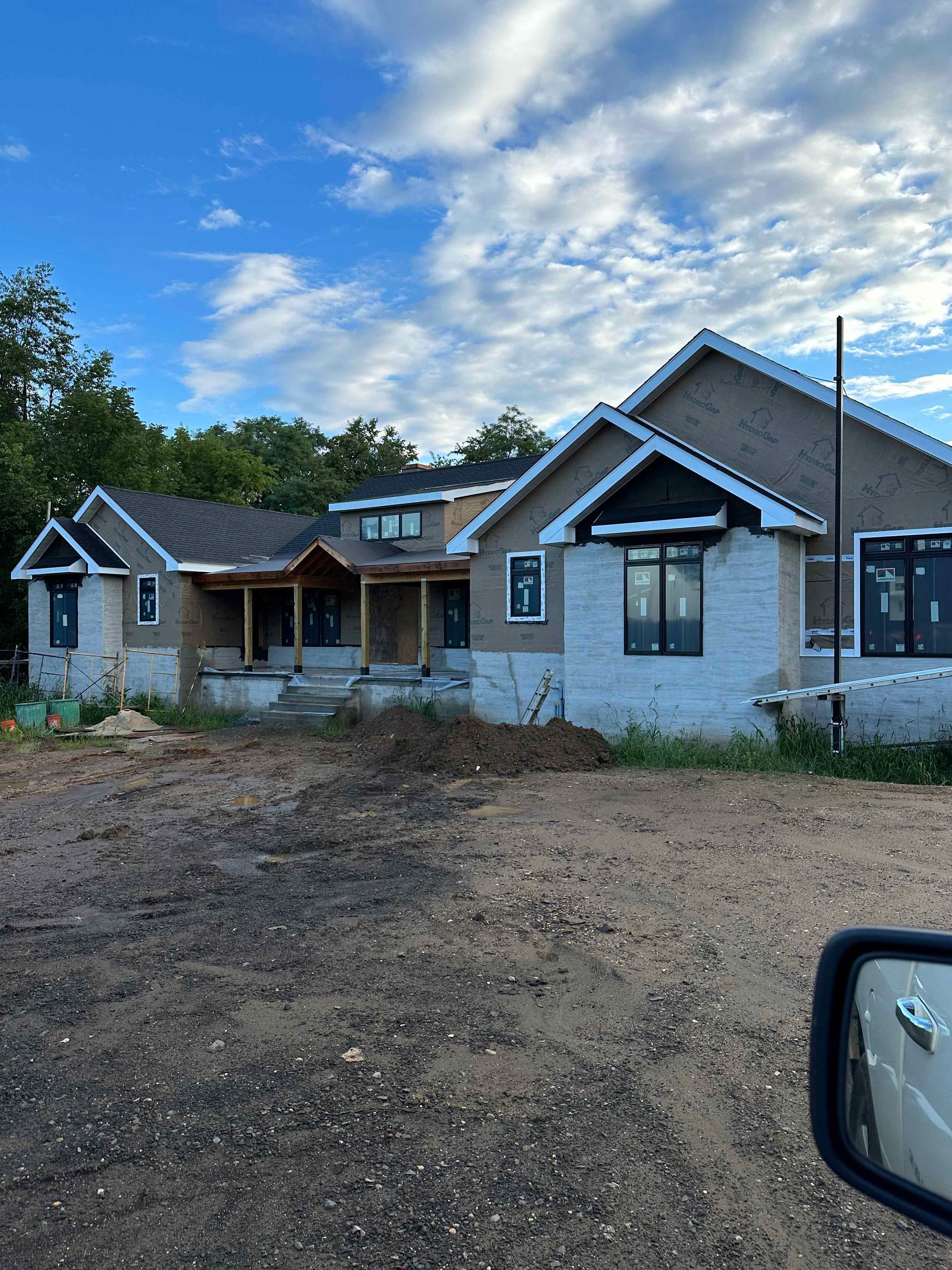 A large house is being built in the middle of a dirt field.