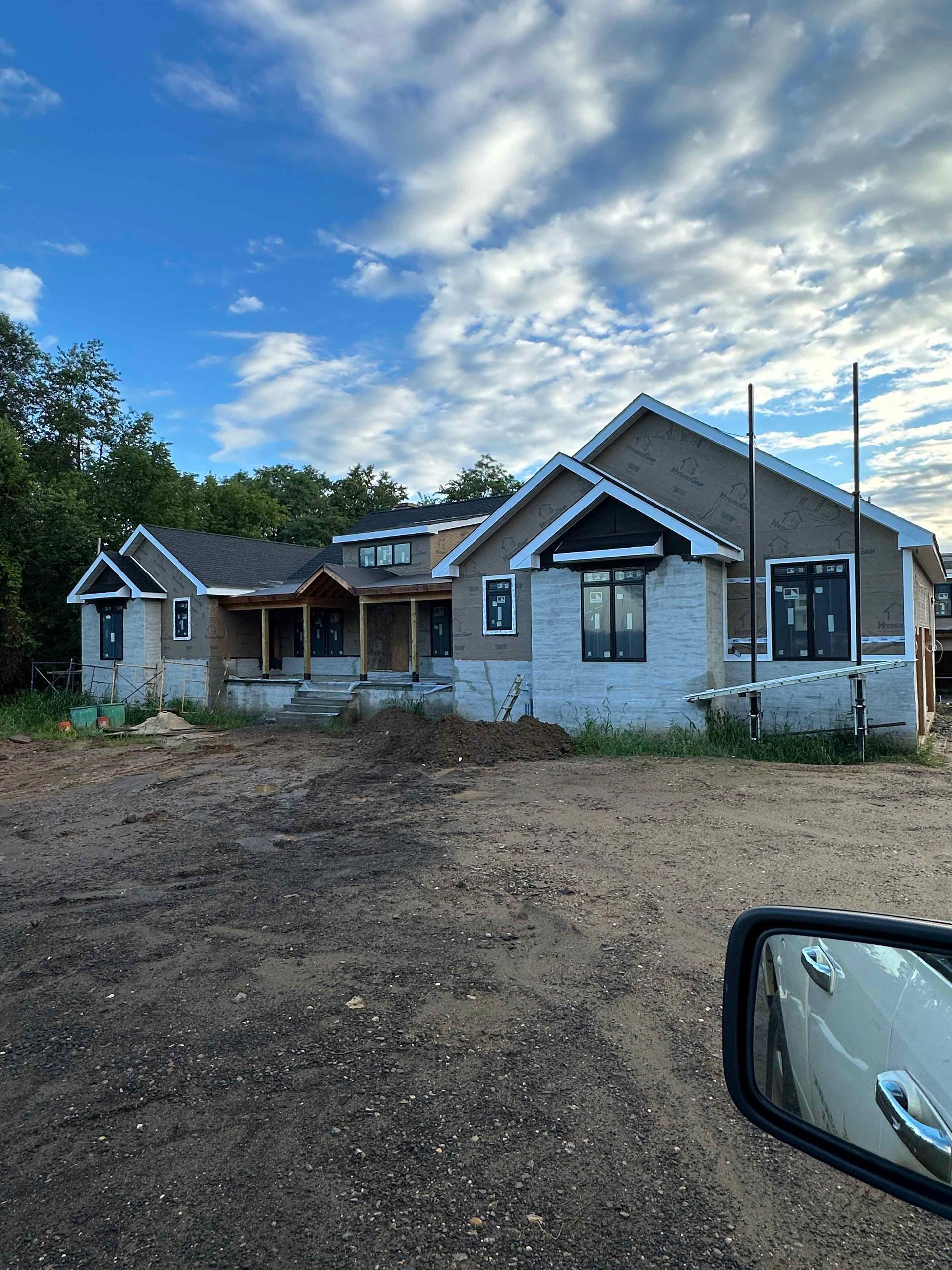 A large house is being built in the middle of a dirt field.