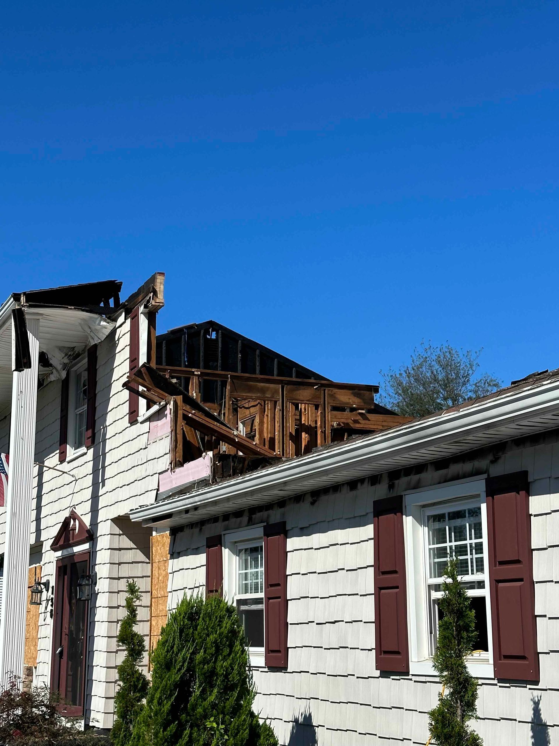A house that has been damaged by a fire with a blue sky in the background.