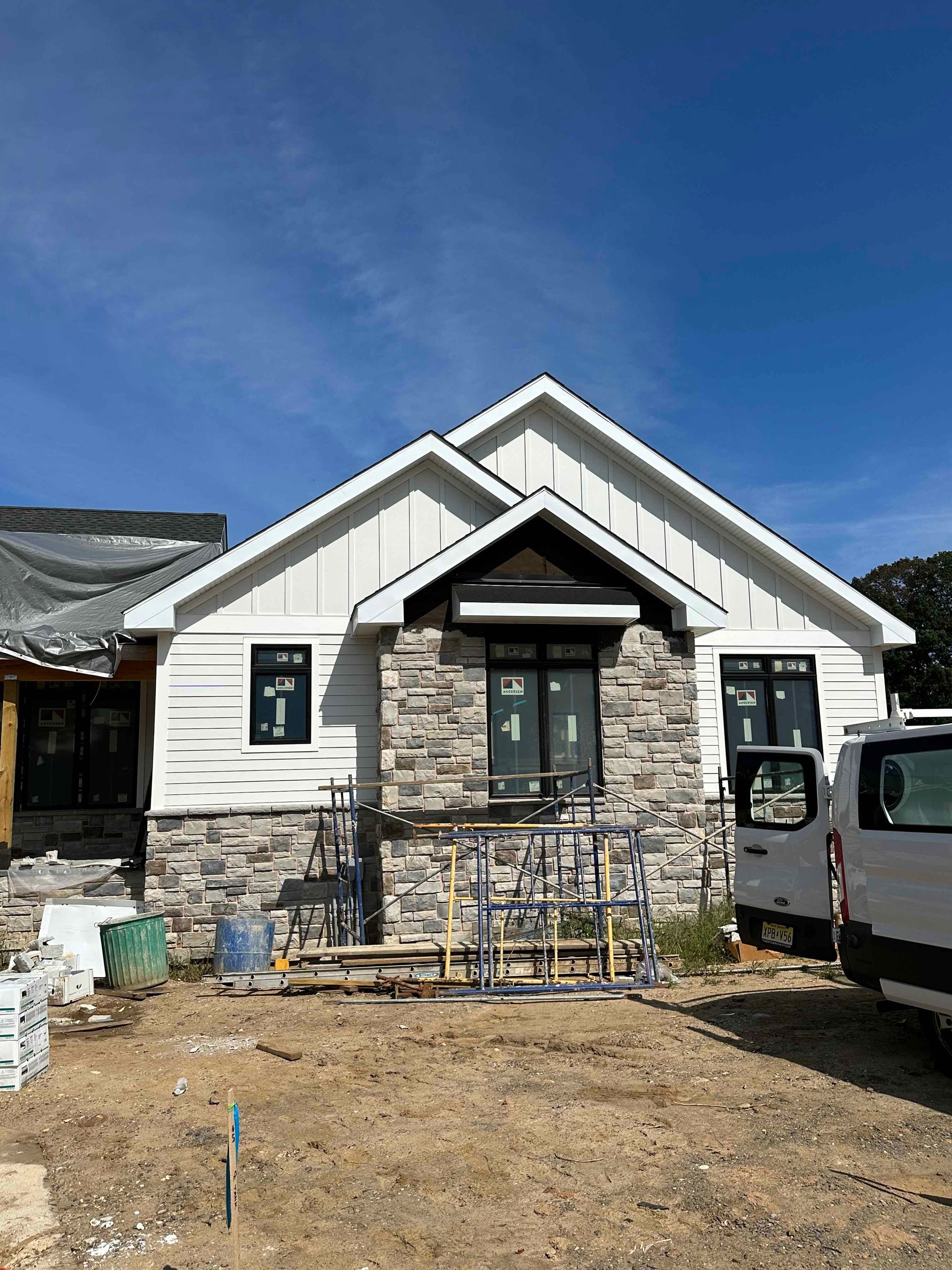 A white van is parked in front of a house under construction.