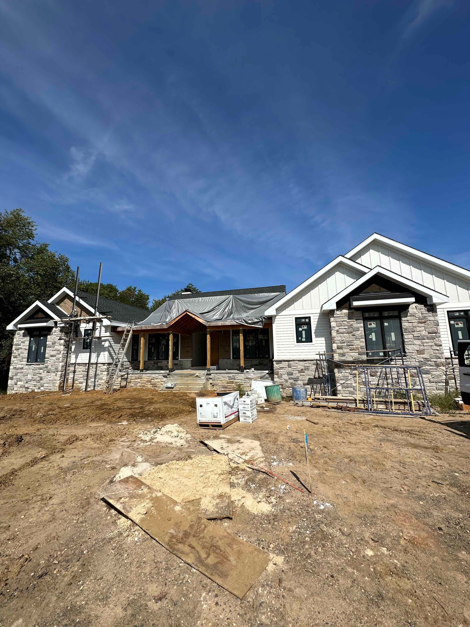 A large house is being built in the middle of a dirt field.
