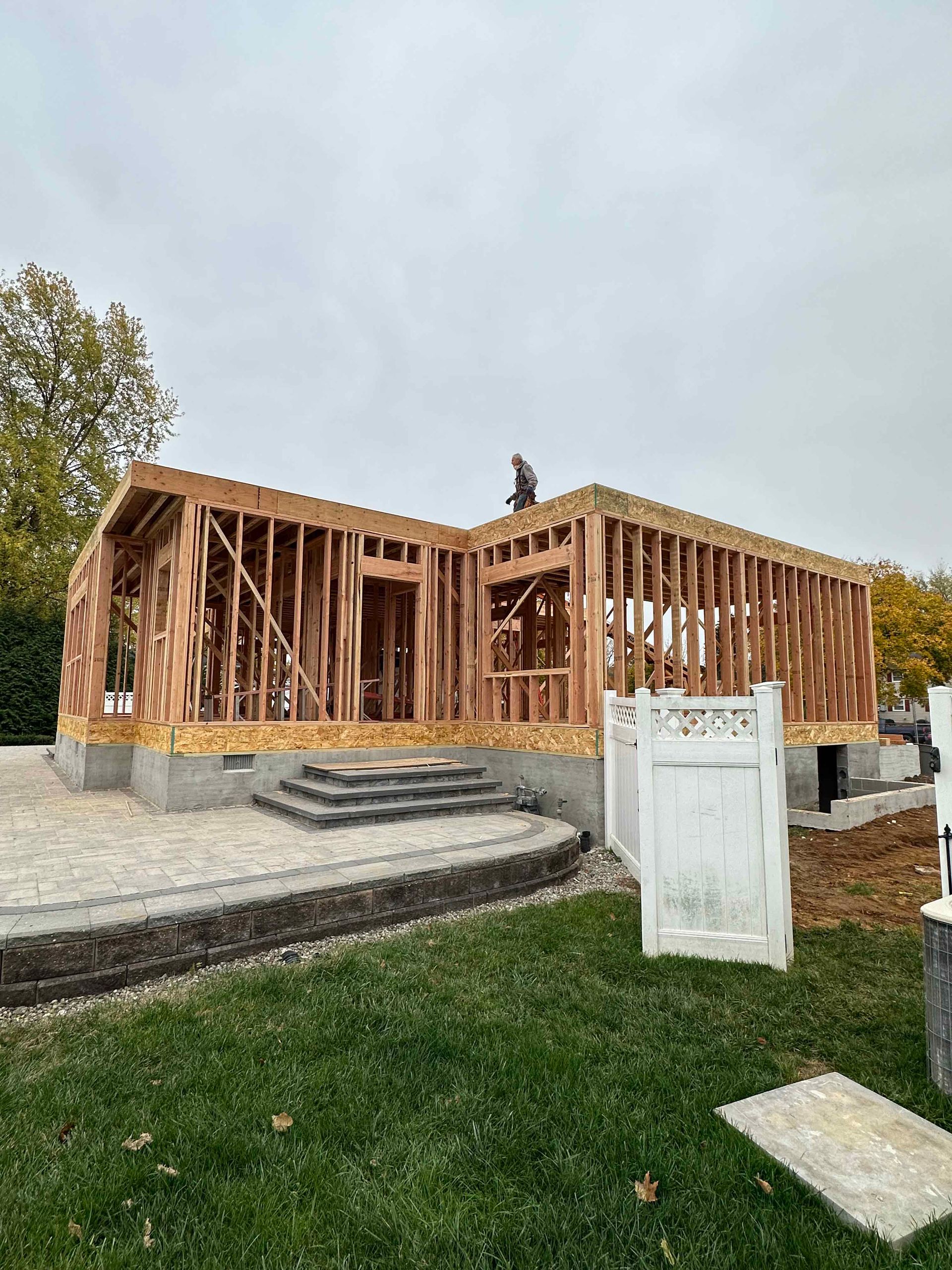 A large wooden house is being built in a backyard.