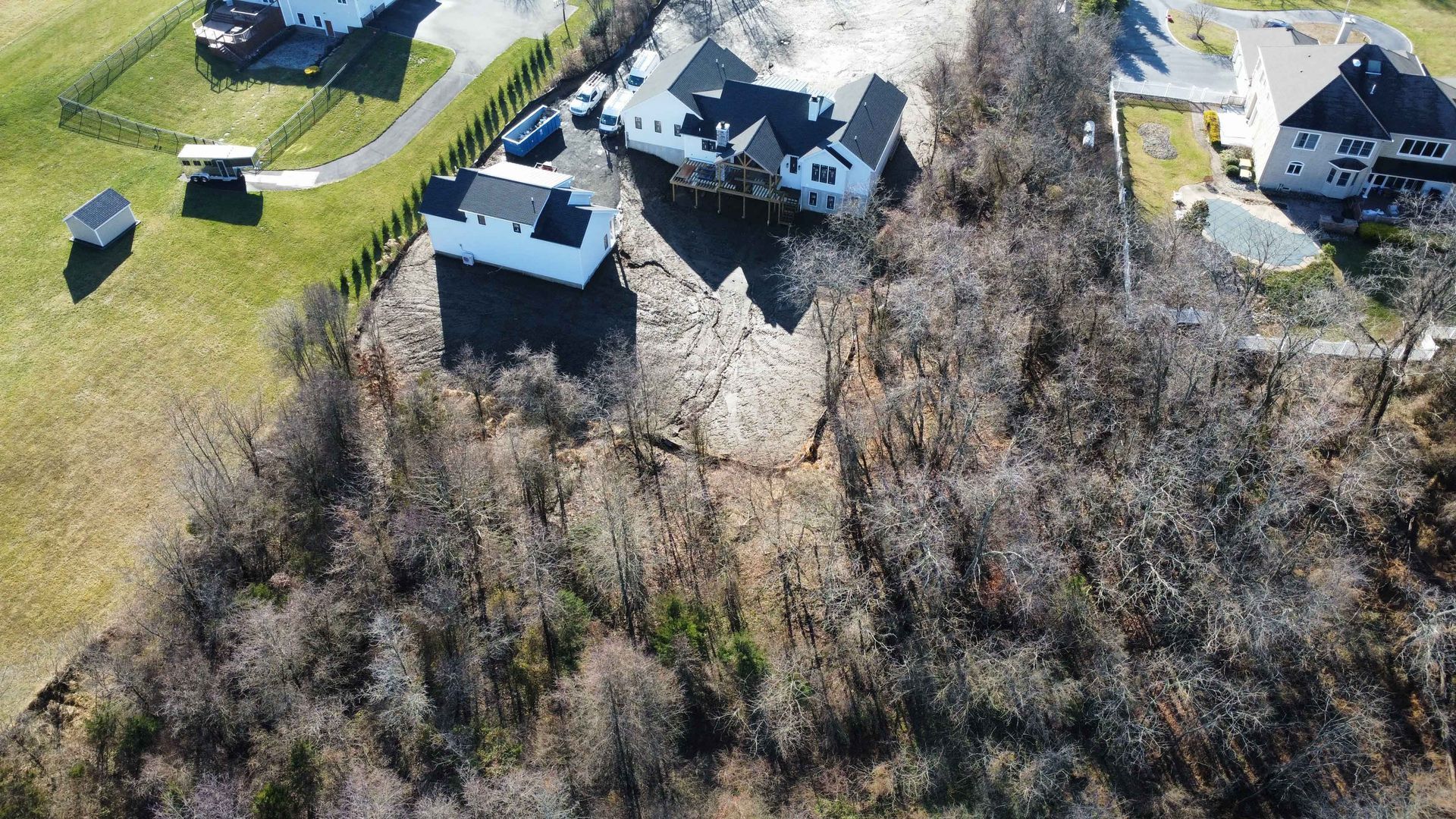 An aerial view of a house on top of a hill surrounded by trees.