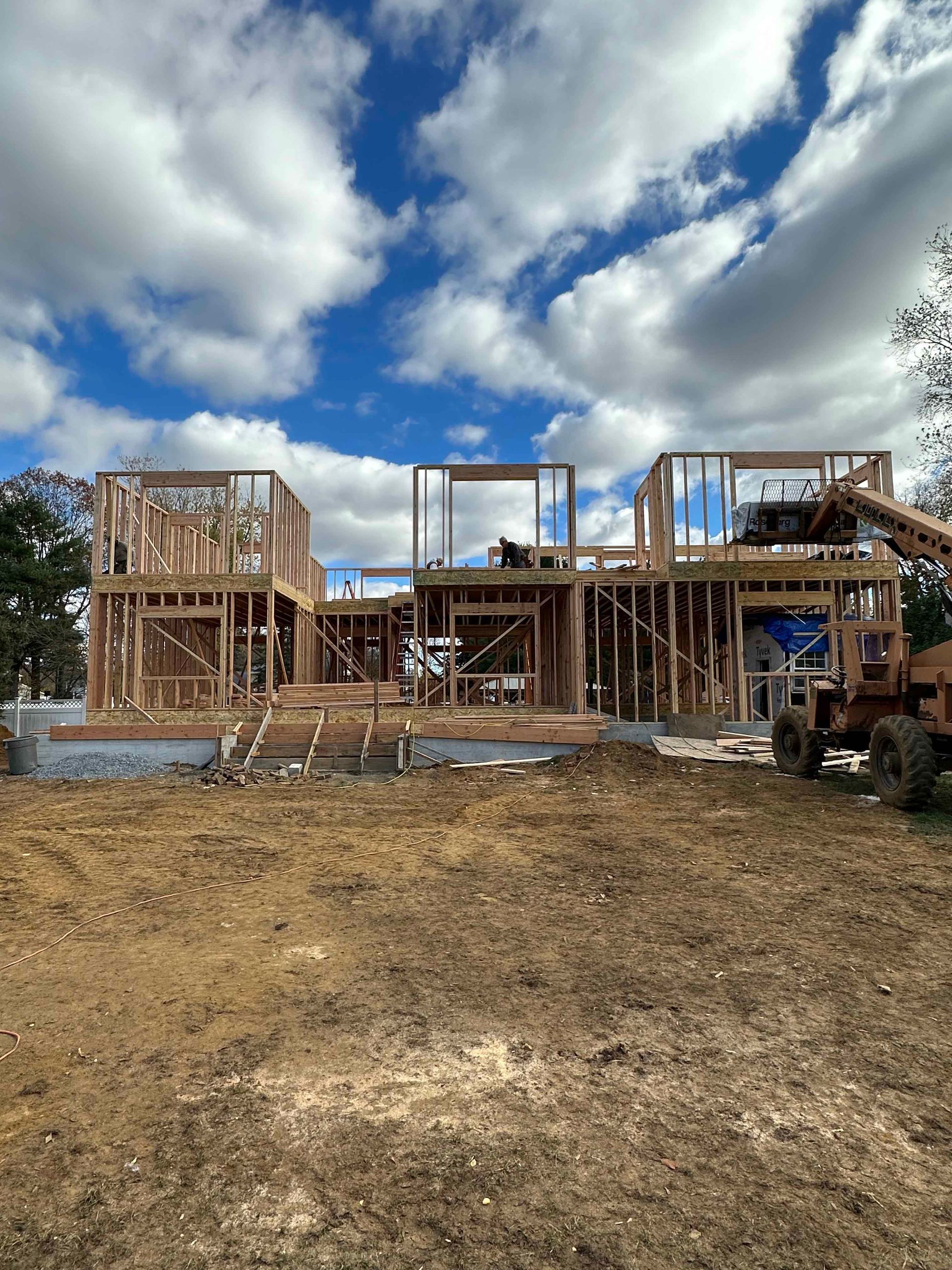 A large house is being built in a dirt field.