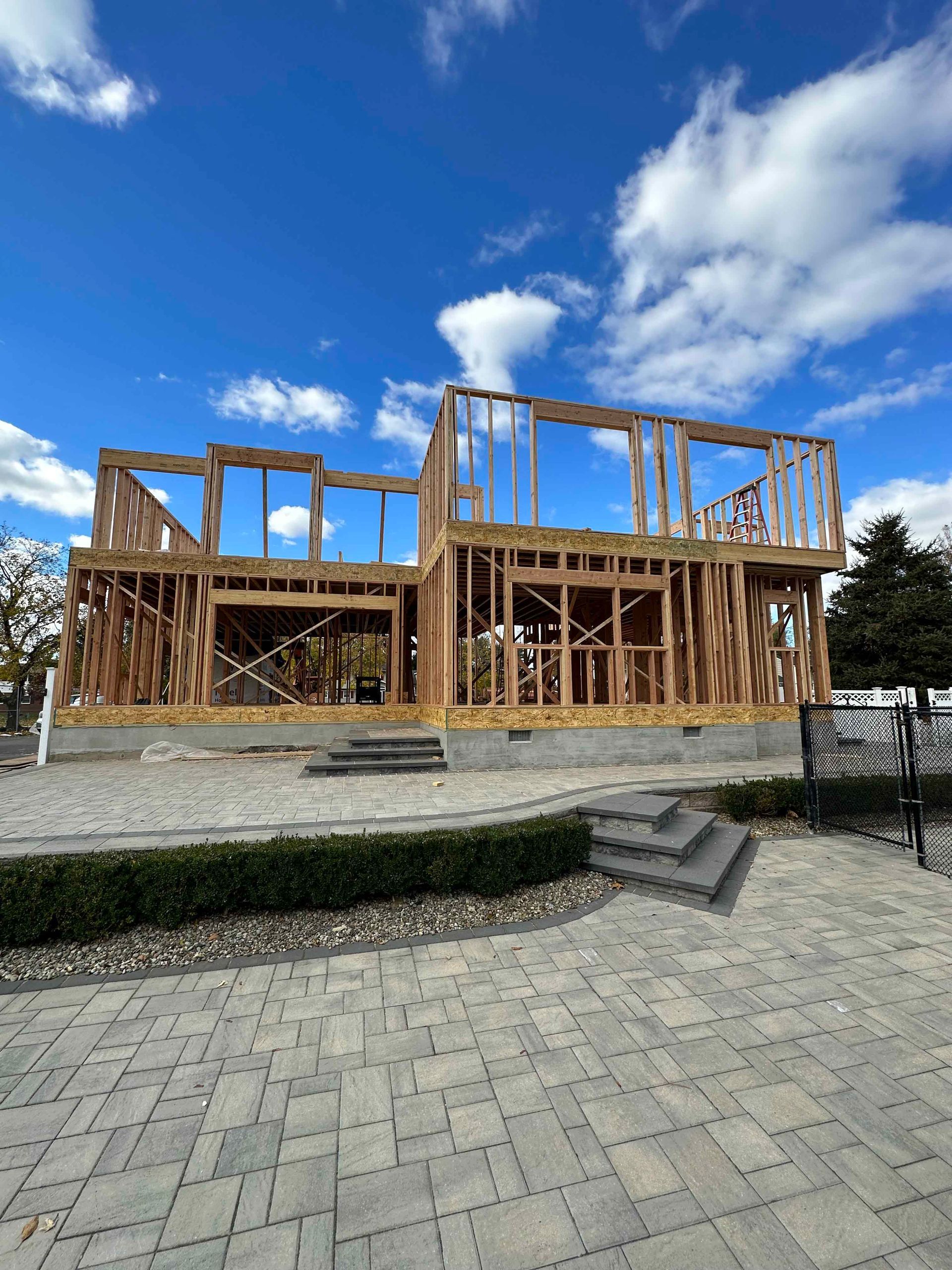 A large wooden house is being built on a brick patio.