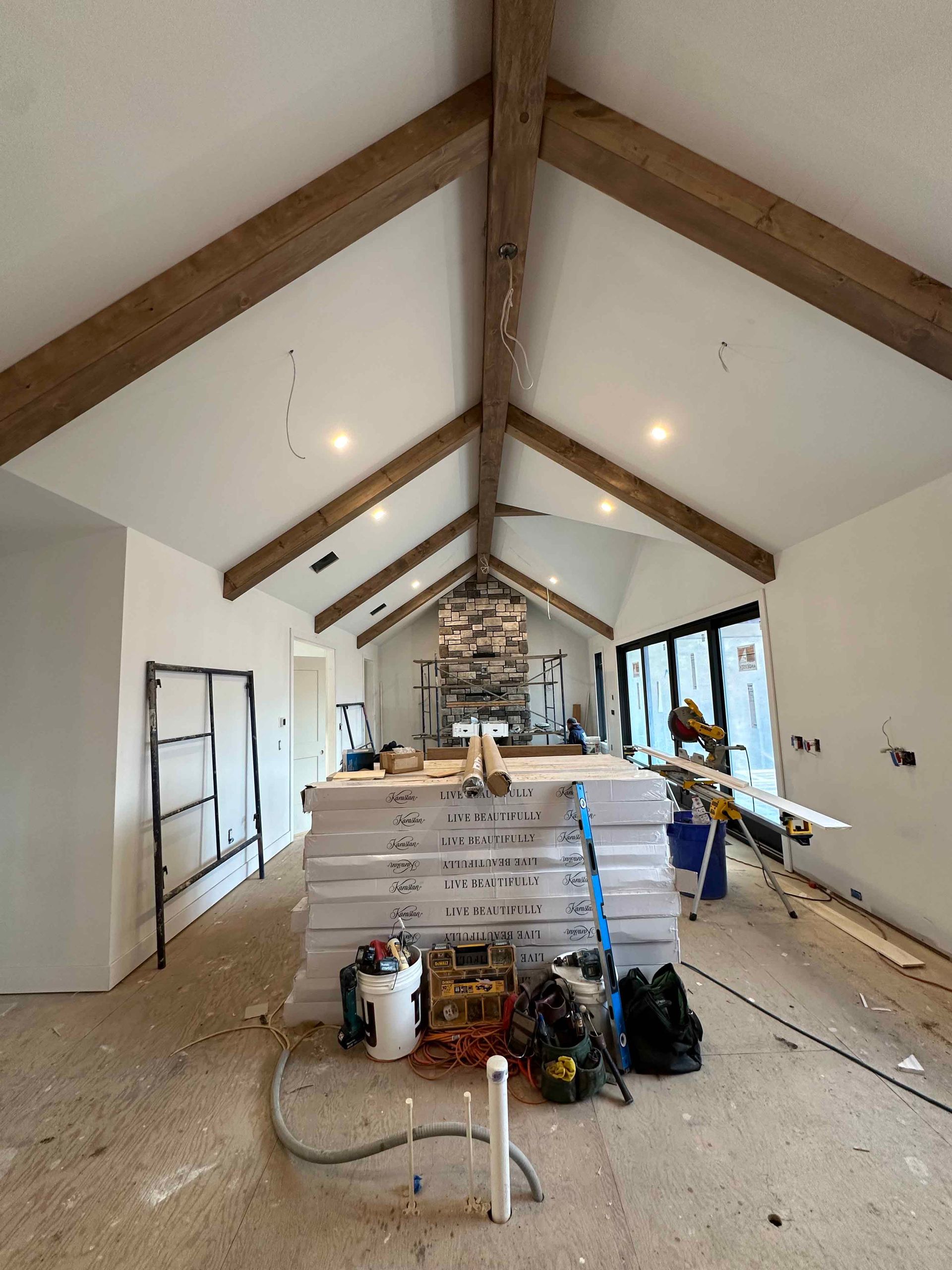A large room with a vaulted ceiling and wooden beams is being remodeled.