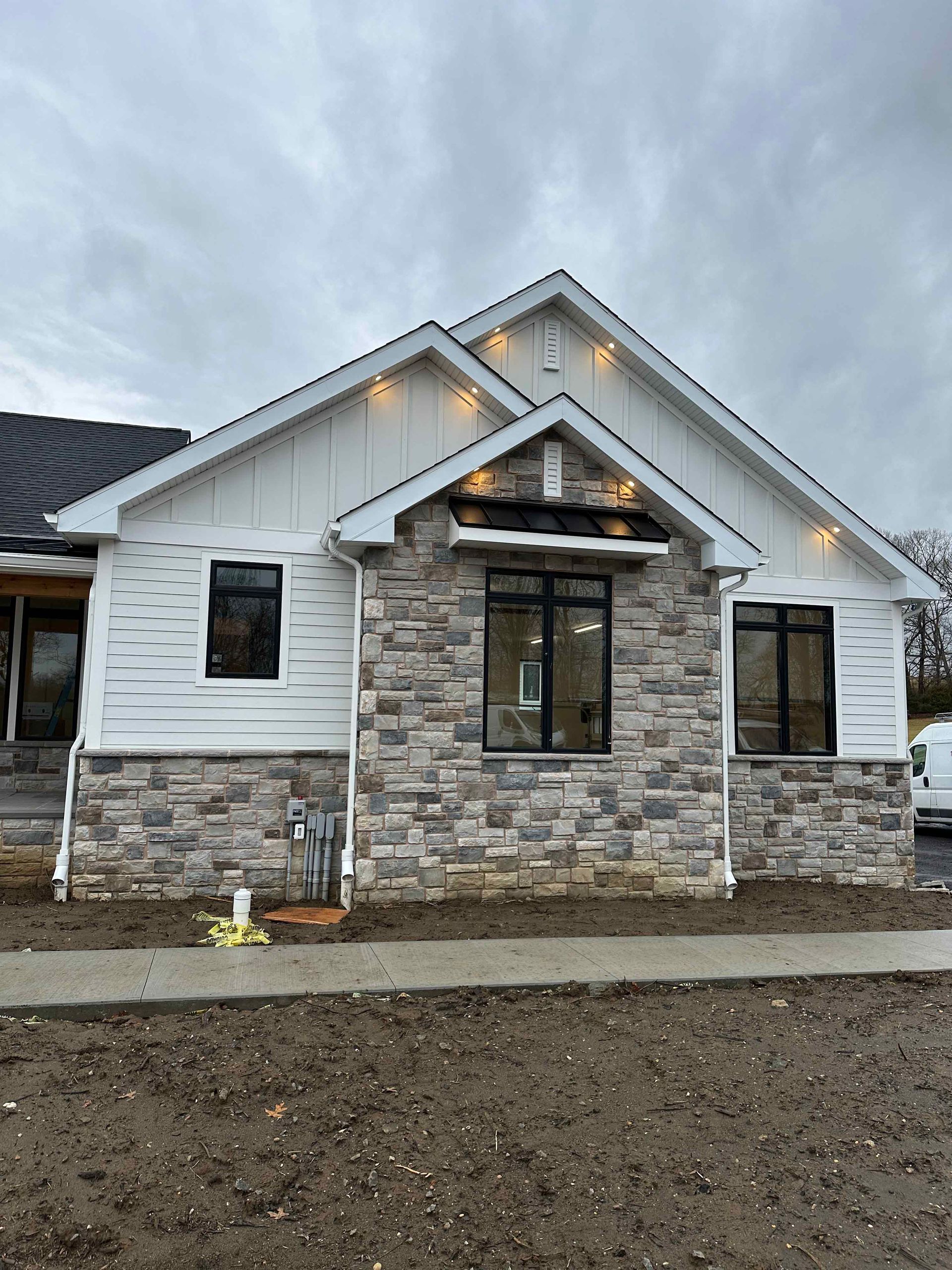 A white house with a stone facade is sitting on top of a dirt field.