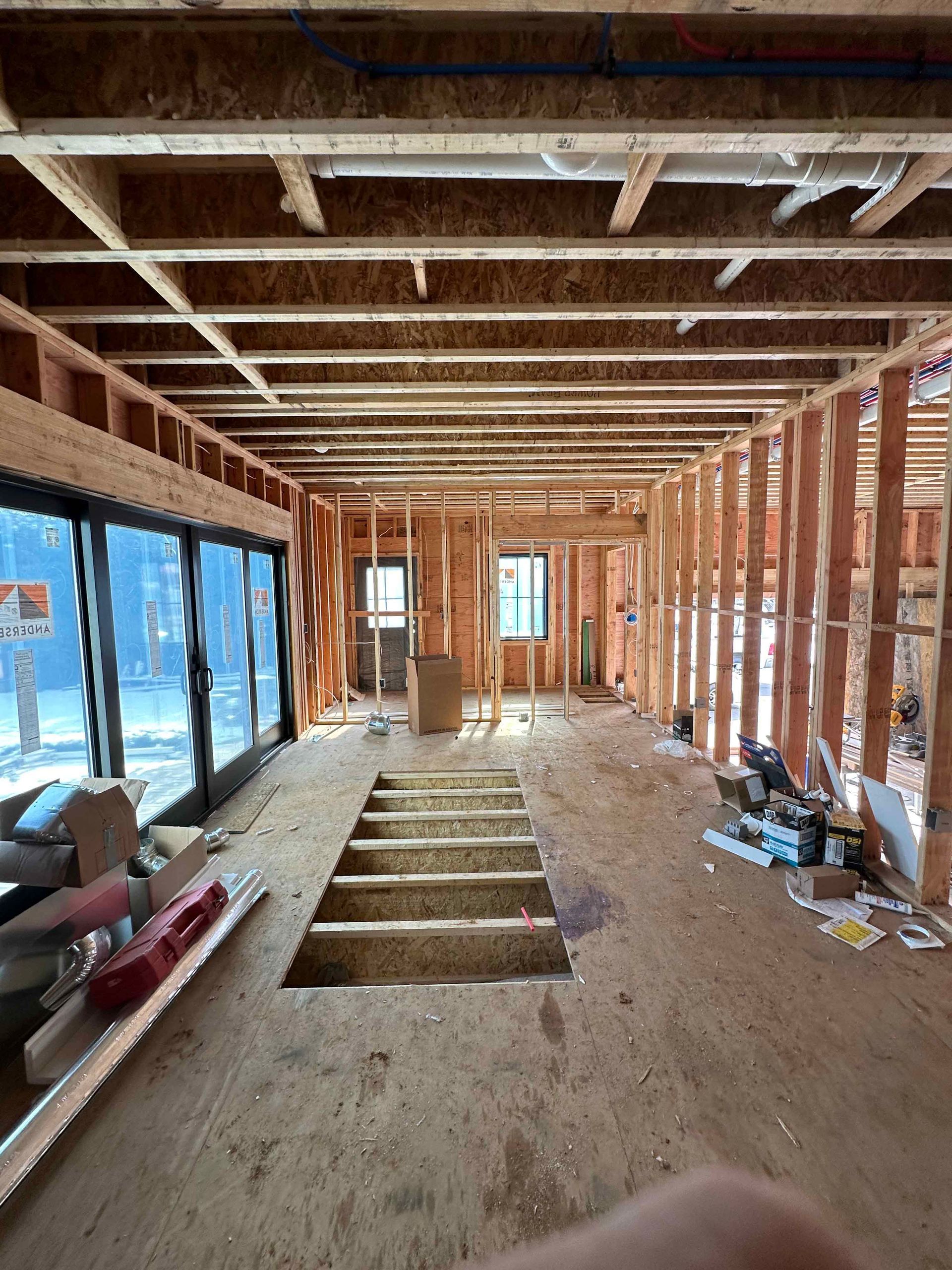 The inside of a house under construction with a hole in the floor.