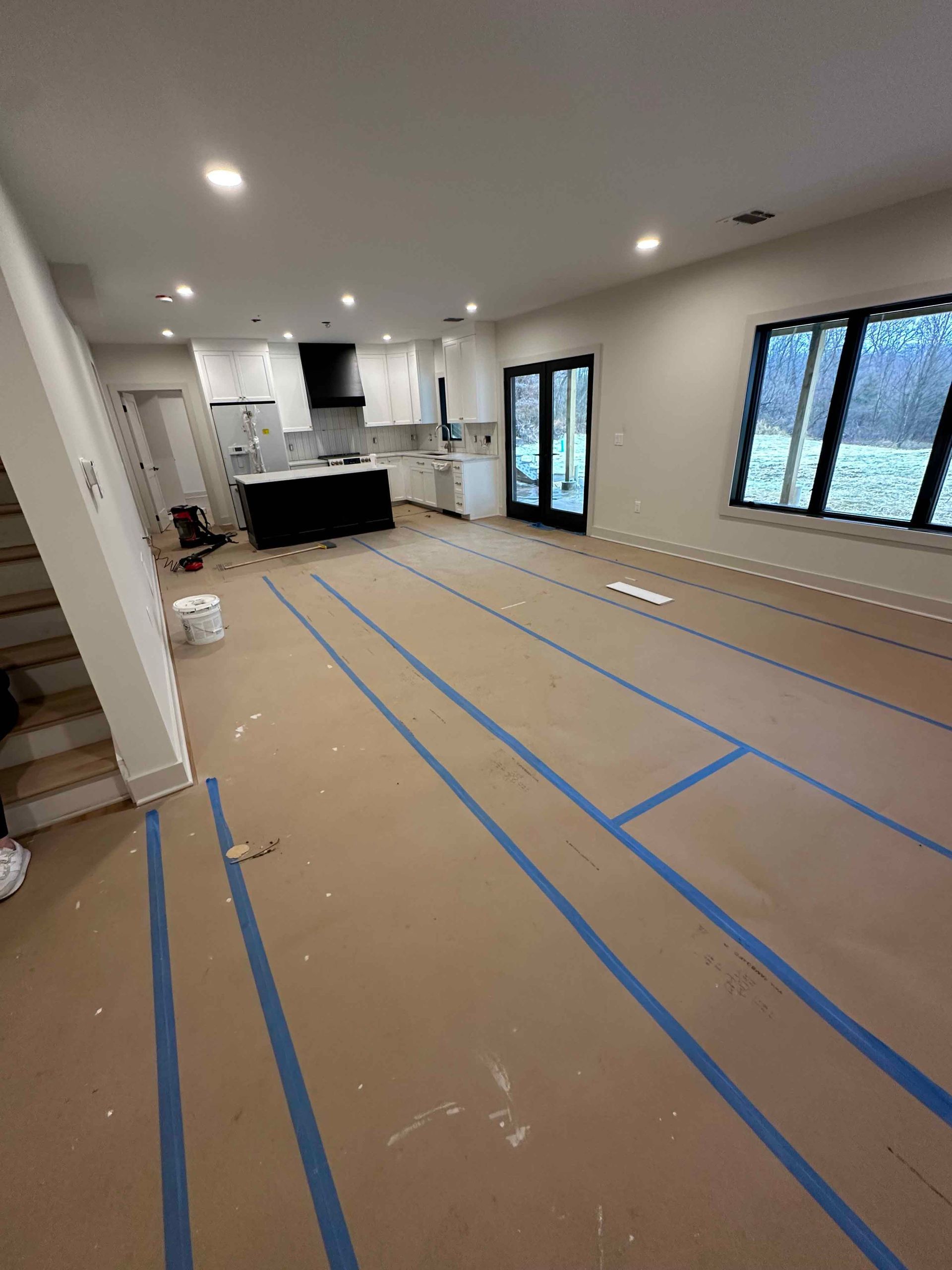 A living room with a lot of blue tape on the floor.