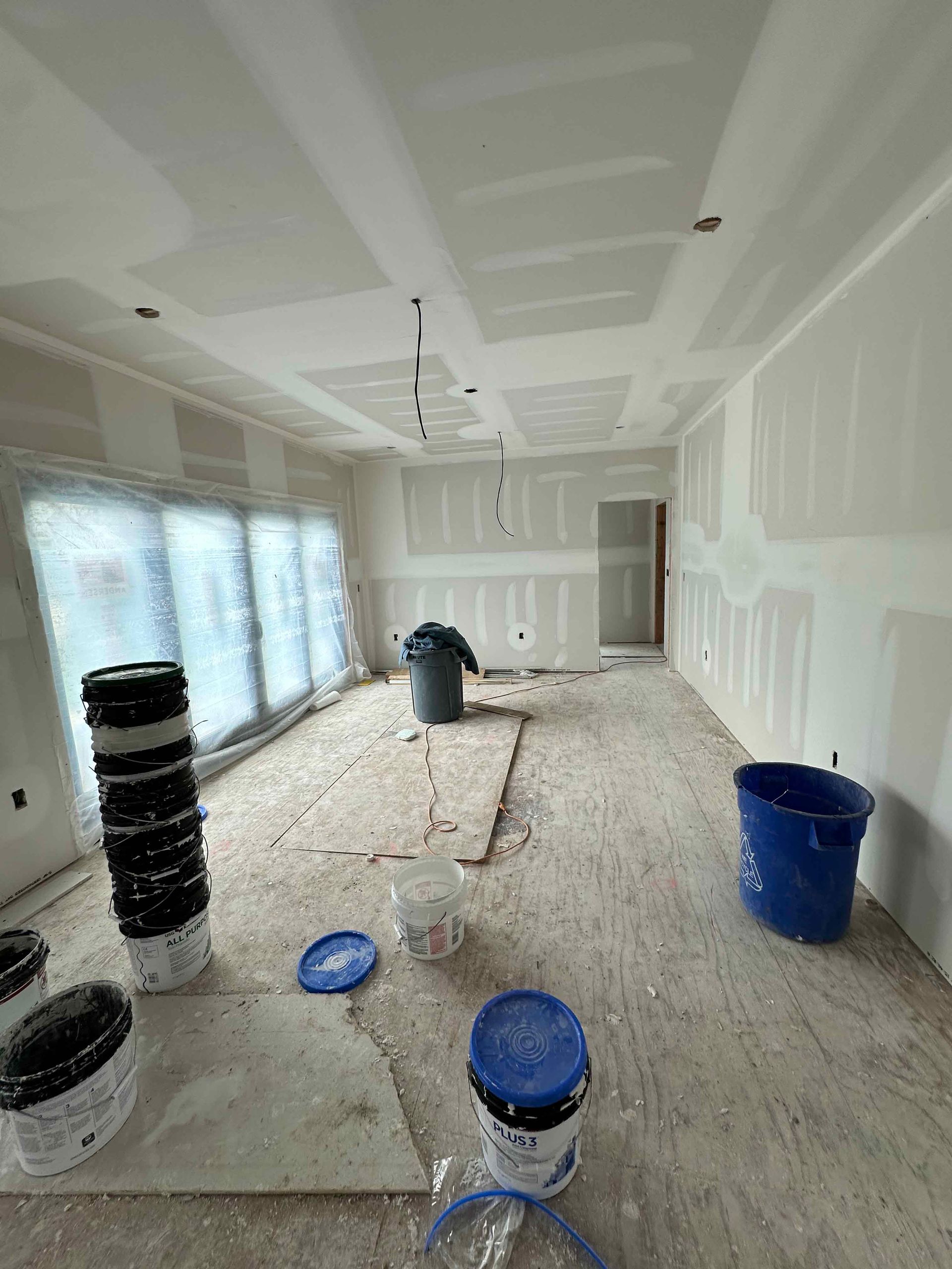 A room that is being painted with buckets of paint on the floor.