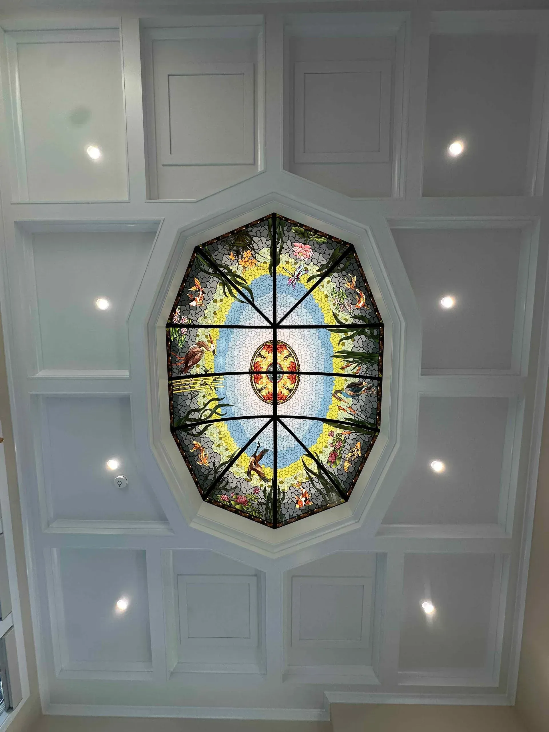 A ceiling with a stained glass window in the middle of it.