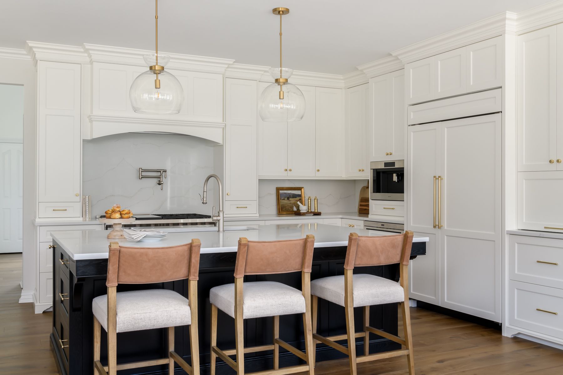 a modern kitchen with white cabinets, a black island, and three bar stools