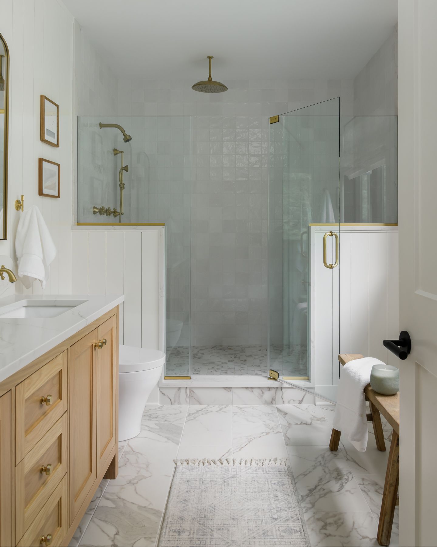 a light-filled bathroom with a wood vanity, walk-in shower, and marble tile floor