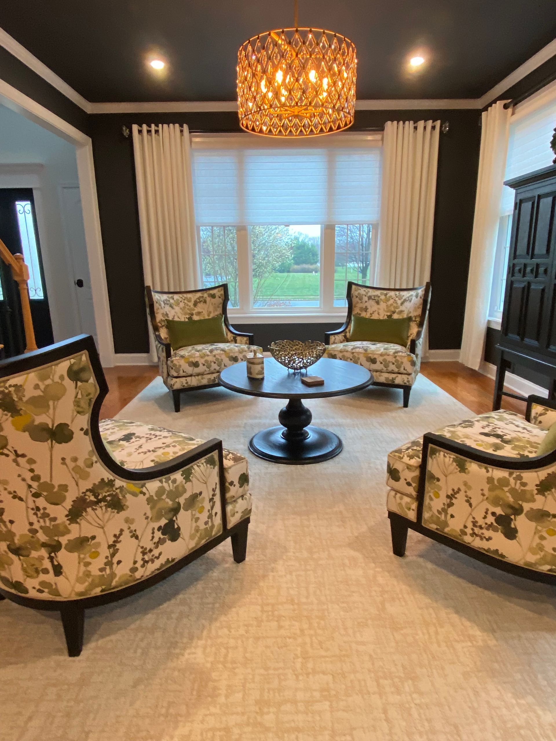 A living room with chairs , a table and a chandelier.