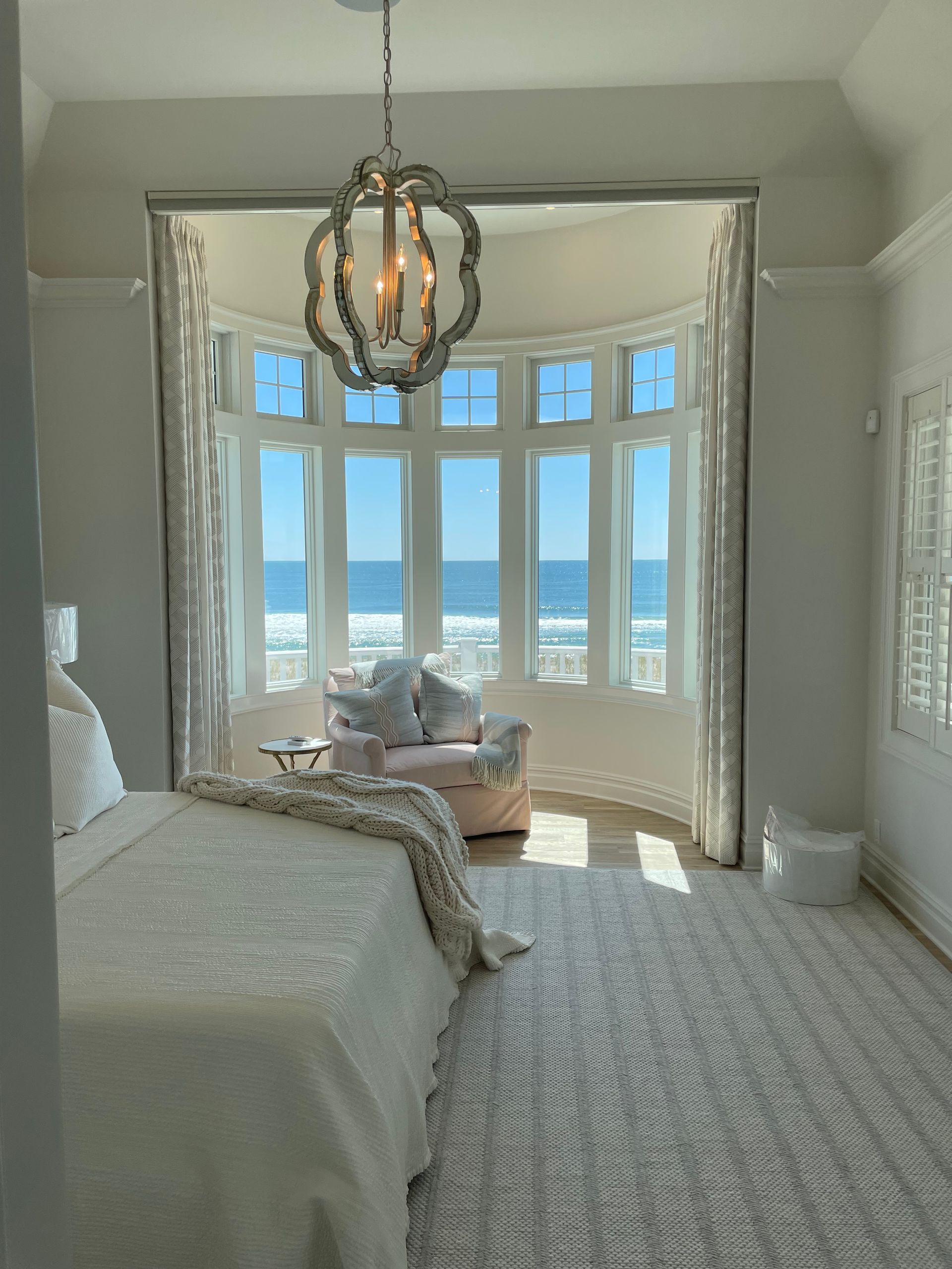 A bedroom with a bed and a large window overlooking the ocean.
