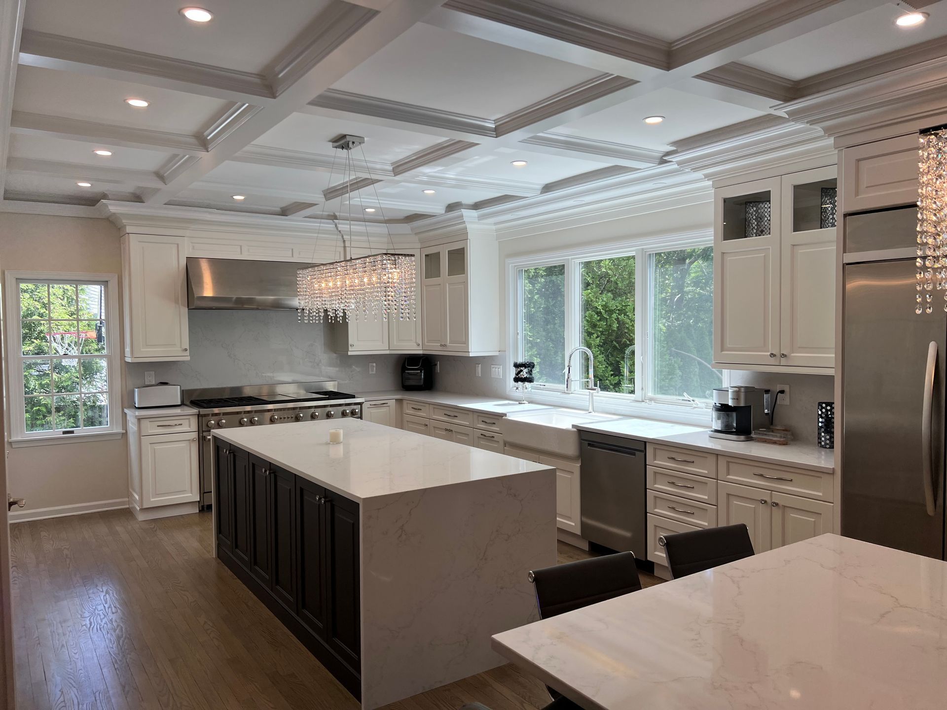 A kitchen with white cabinets and stainless steel appliances and a large island